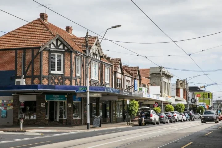Hawthorn Road Caulfield North street with small shops and parking vehicles, featuring old brick buildings with exposed timber framing.