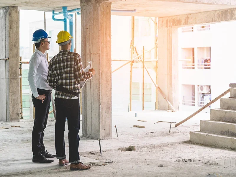 Property developers in hard hats holding documentation whilst standing in a semi-completed apartment build