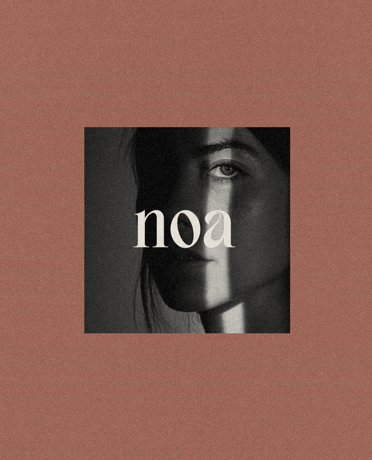 Black and white portrait of a woman's face with a vertical shadow split, with the word "noa" in the center.