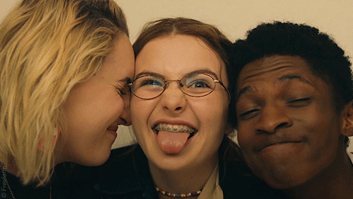 Three young people making funny faces close together, smiling and sticking out their tongues.