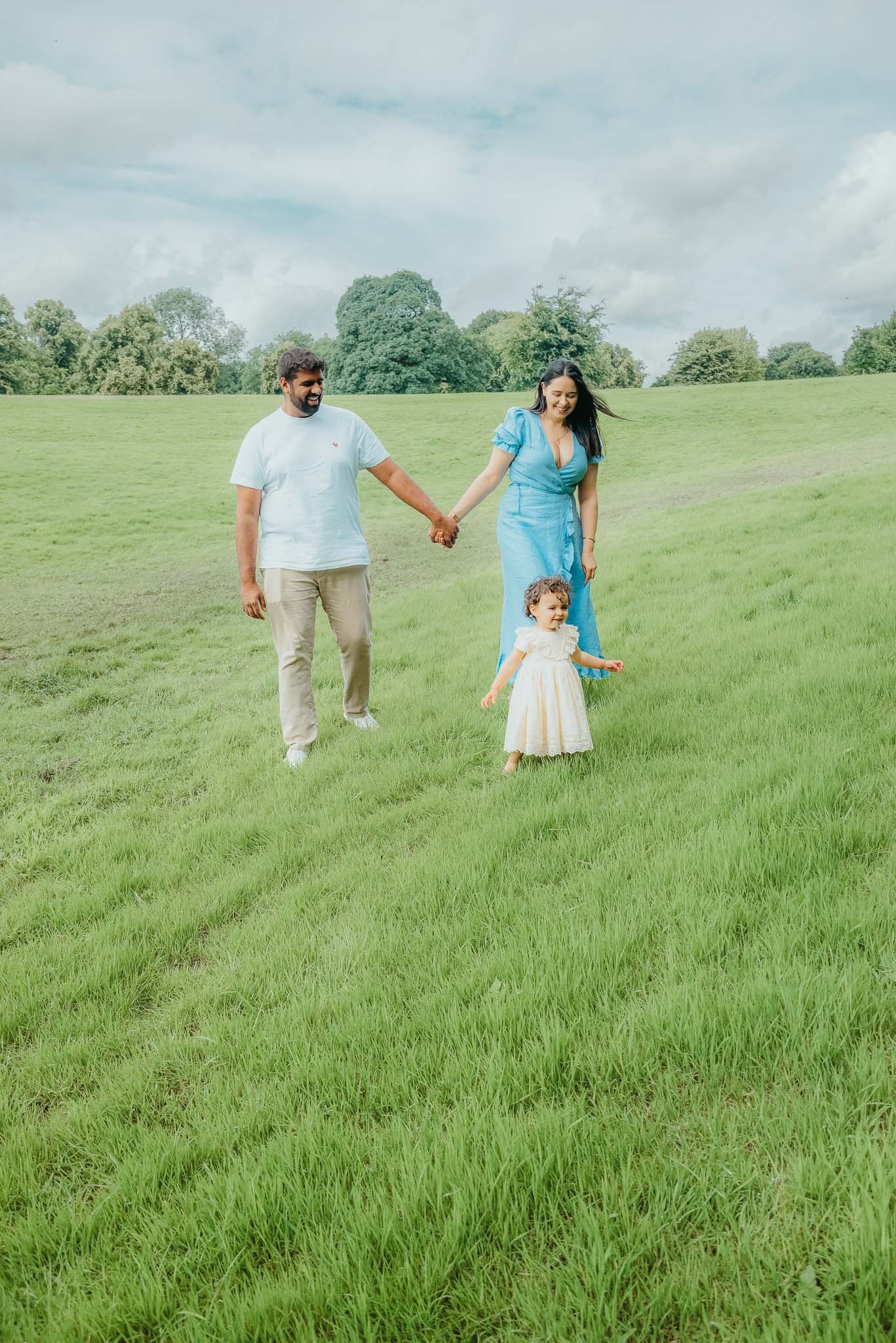 Family walking in a grassy field holding hands
