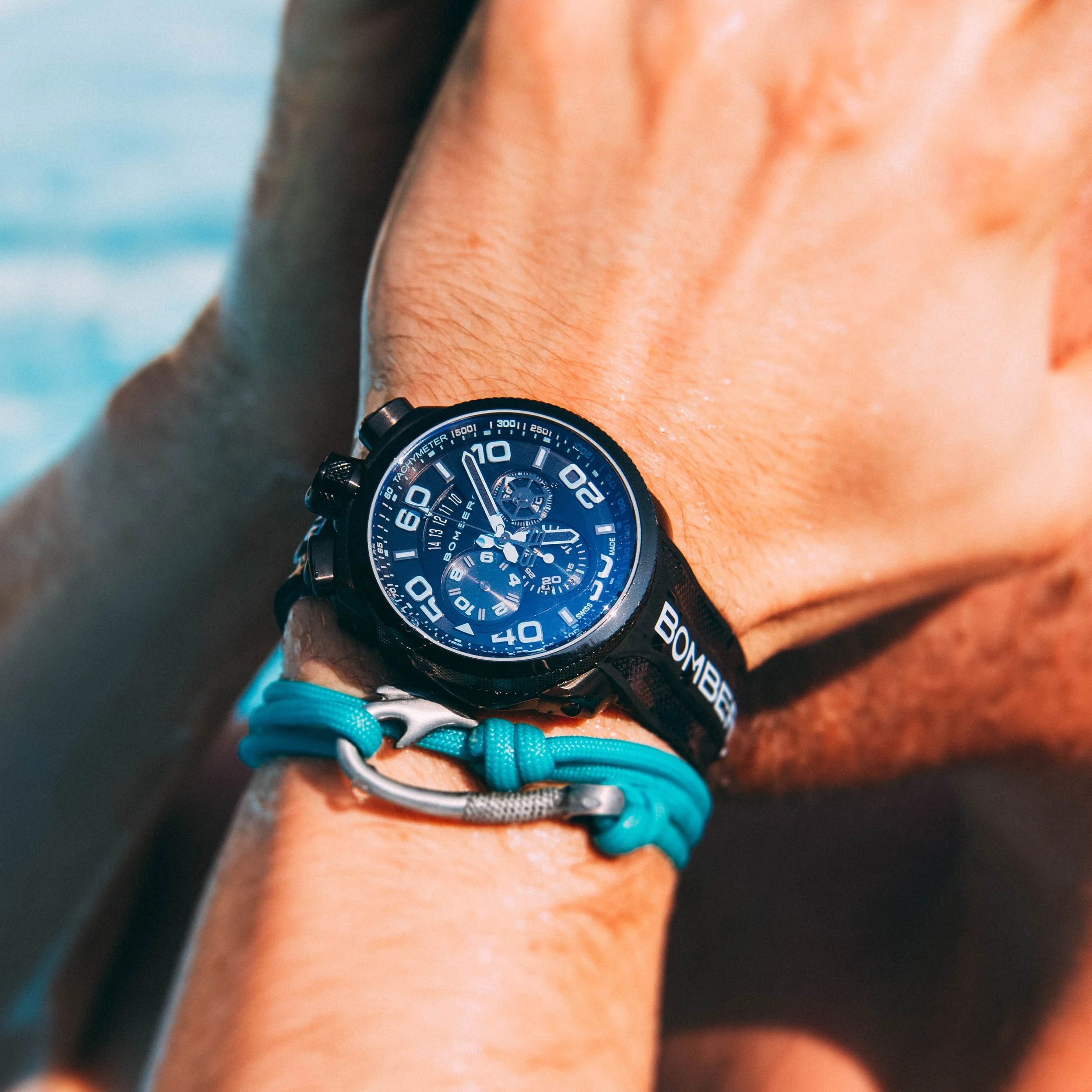 Montre Bomberg avec cadran bleu sur un poignet, porté avec un bracelet en paracorde bleu et un mousqueton.