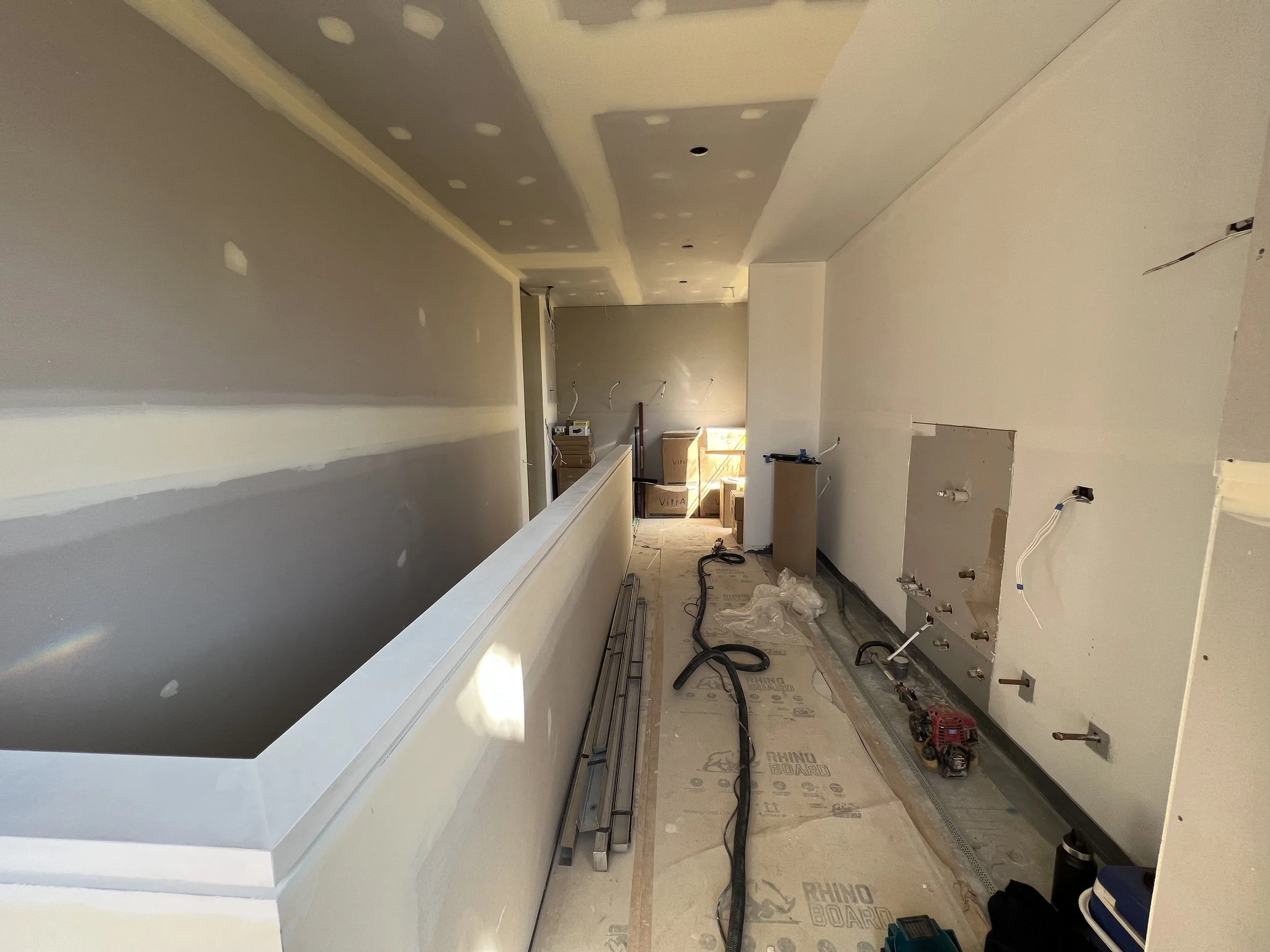 A two-story house with brick exterior, modern black additions, and large windows, surrounded by greenery and a well-maintained lawn under a blue sky.