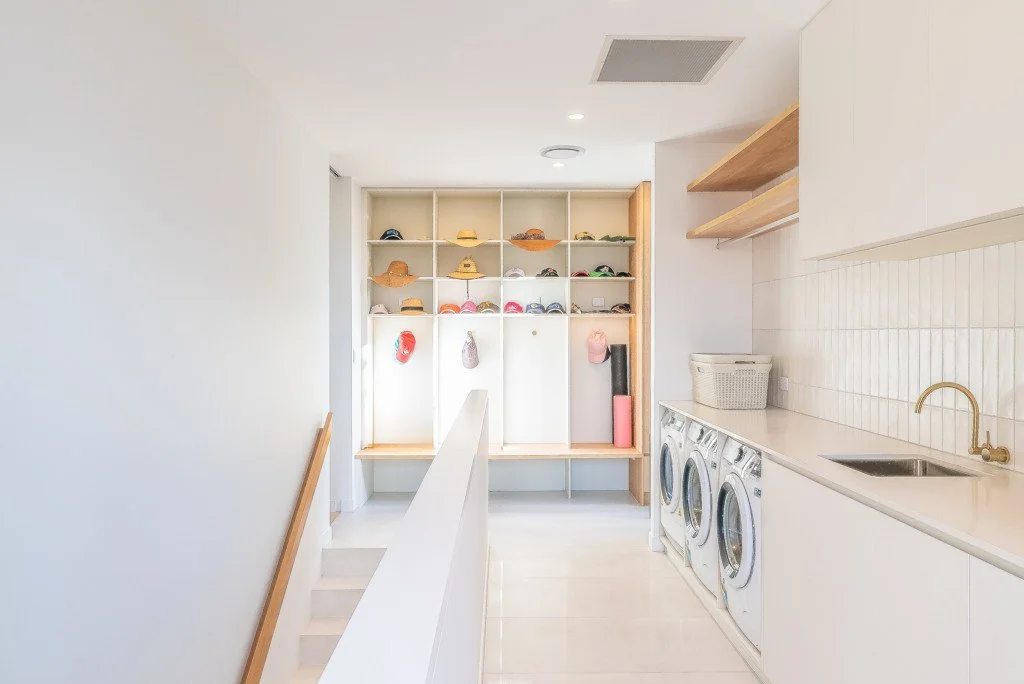 Laundry room with washing machines, cabinets, and shelves with hats and other items