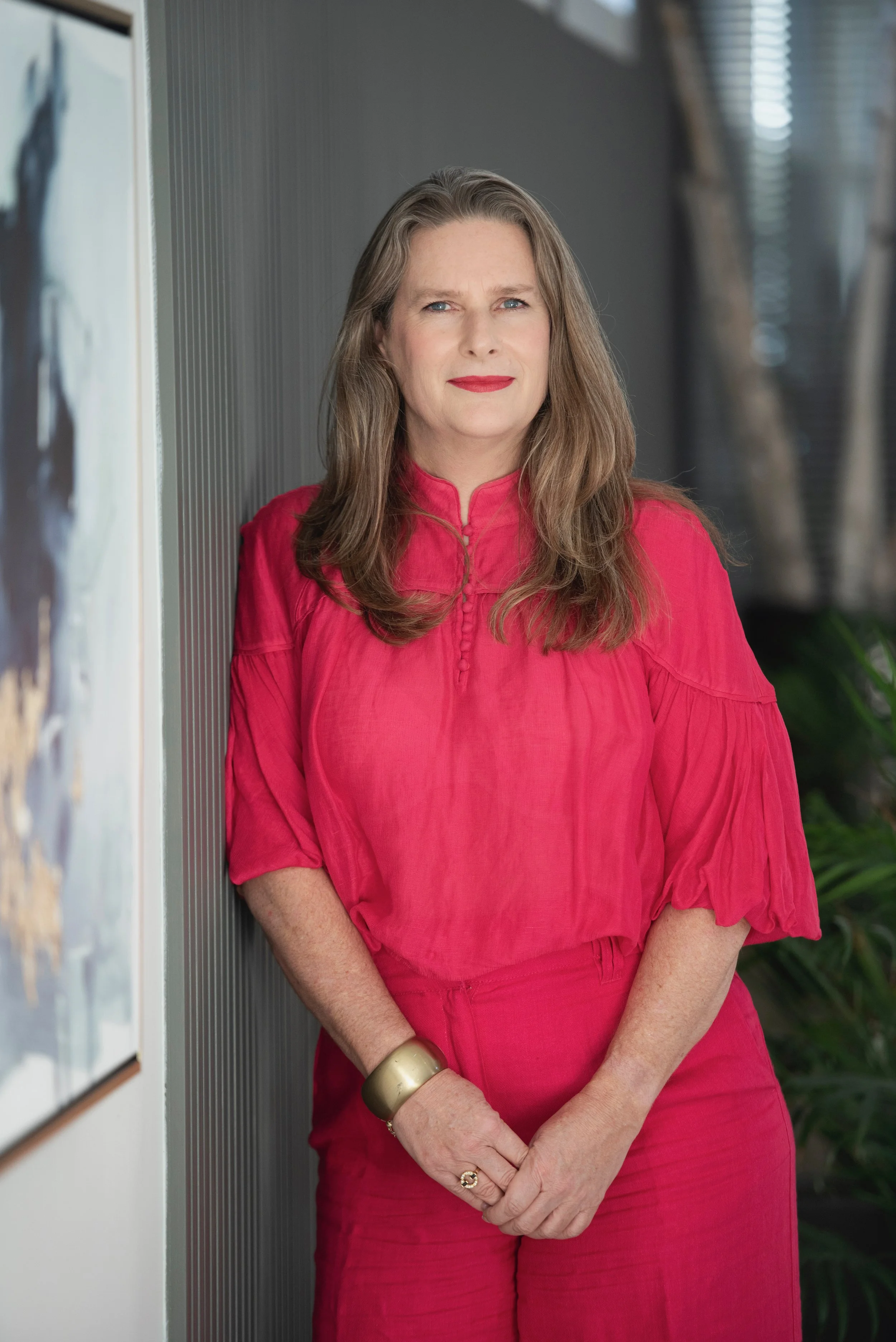 Portrait of Samantha, founder of Hawksburn Design, standing in a contemporary interior space wearing a vibrant pink outfit.