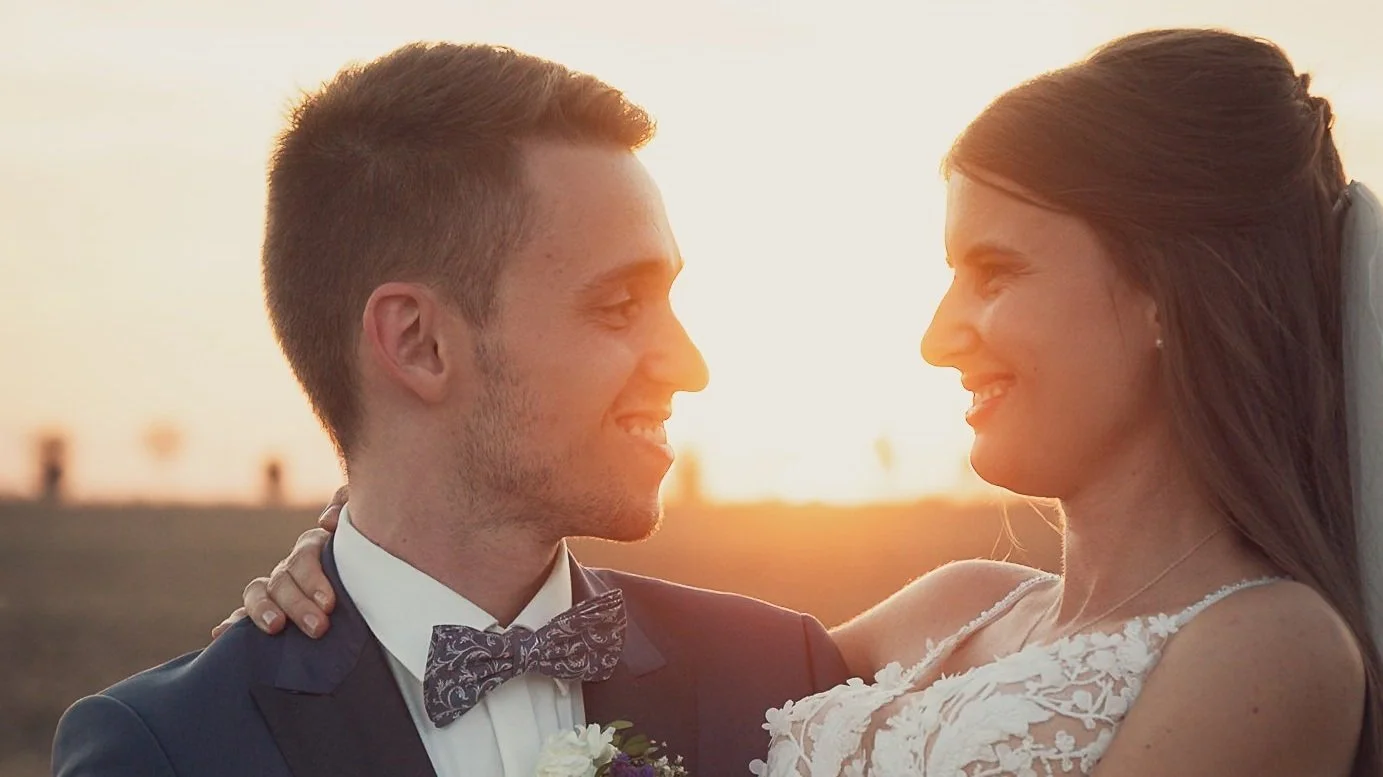 A smiling bride and groom looking at each other during sunset on their wedding day.