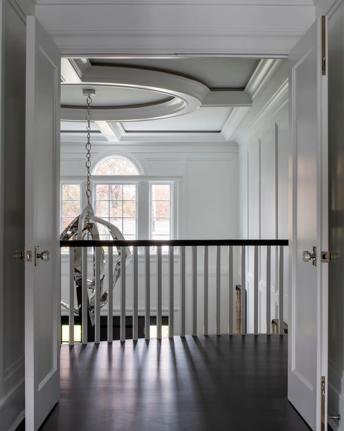 From the moment you pass through the double doors, the master suite unfolds with quiet drama. The entry sets the tone with architectural detail and sculptural lighting, leading you into a space layered in soft grays, velvets, and tailored textures.
A