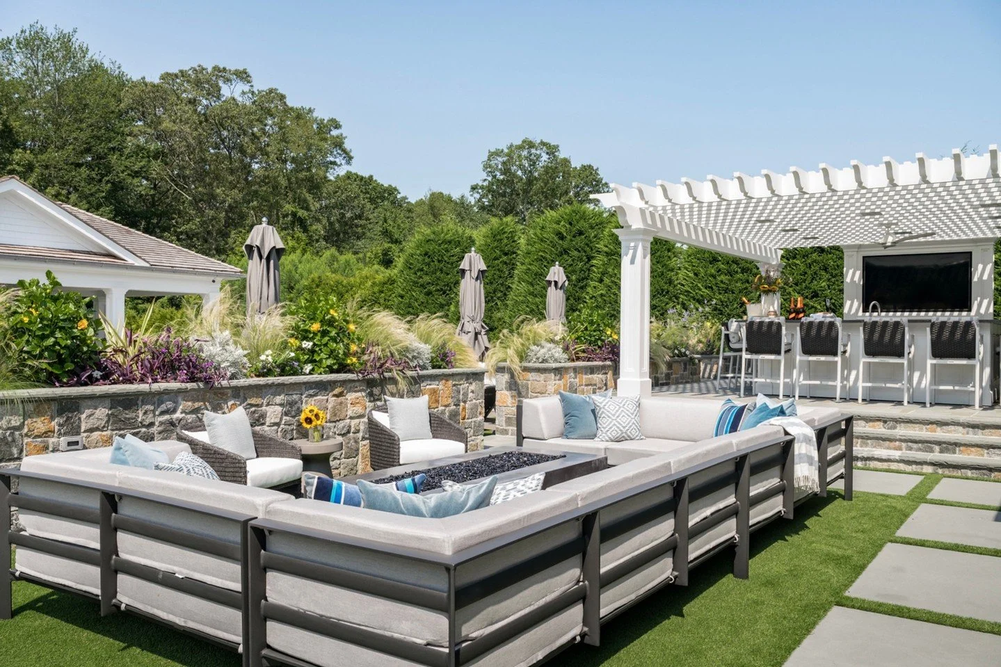 Moving to the second seating area ✨
Closer to the house, this cozy lounge was designed for evenings by the fire. Framed by lush landscaping and natural stone, the oversized sectional creates an inviting place to gather, unwind, and stay awhile.
Soft 