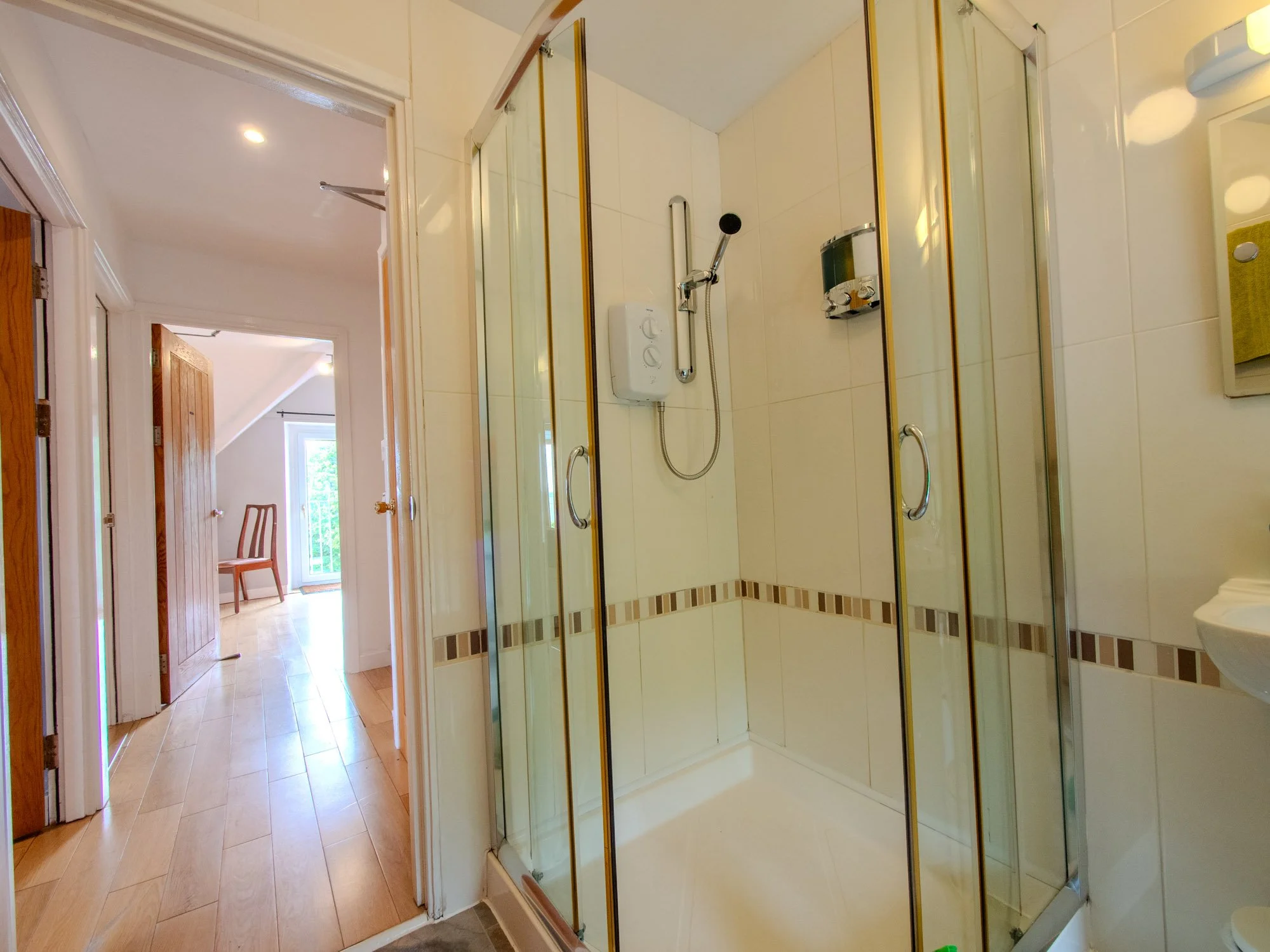 Shower stall with glass doors, white tiles, and shower fixtures in a bathroom