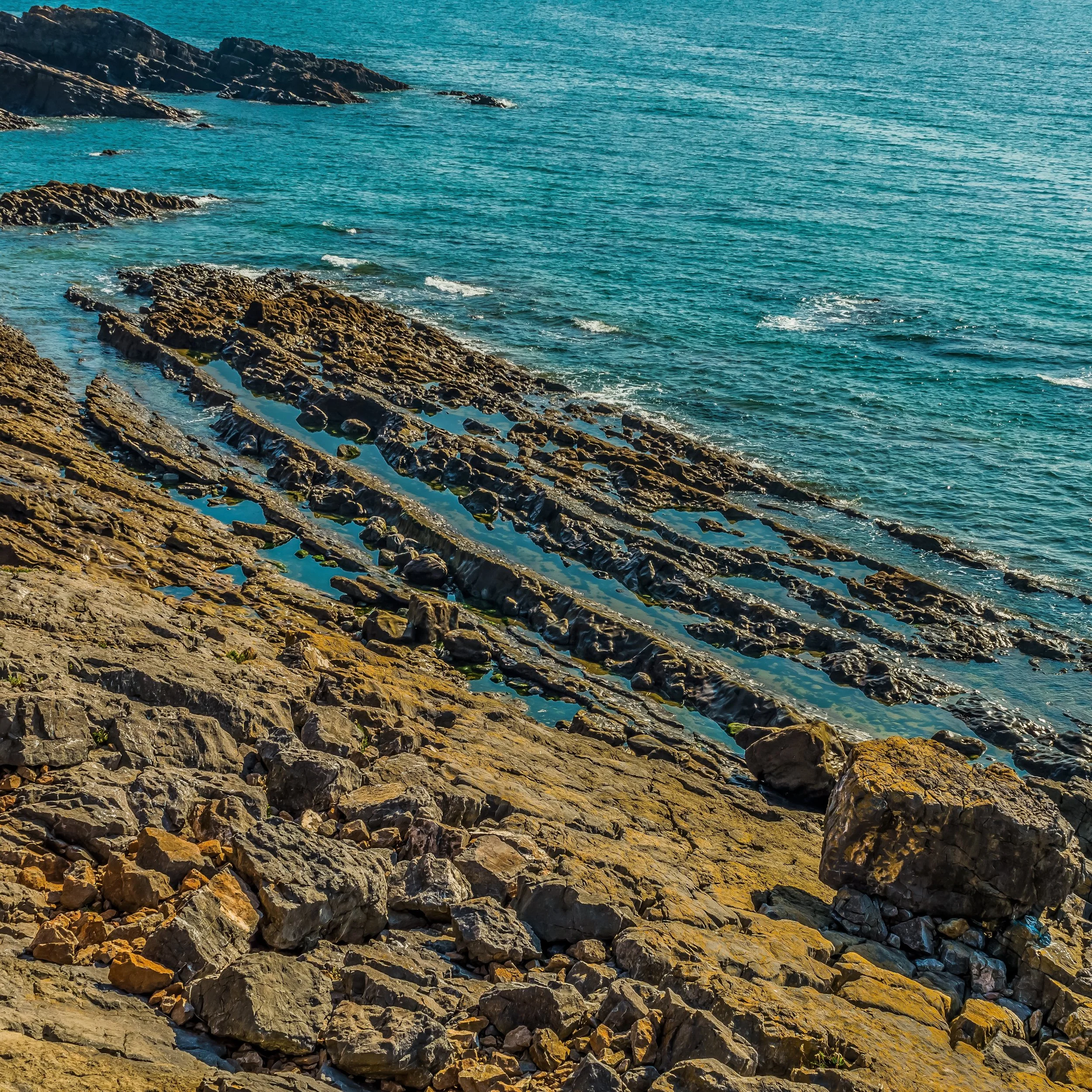 Rocky coastline with turquoise ocean water and rugged rock formations.