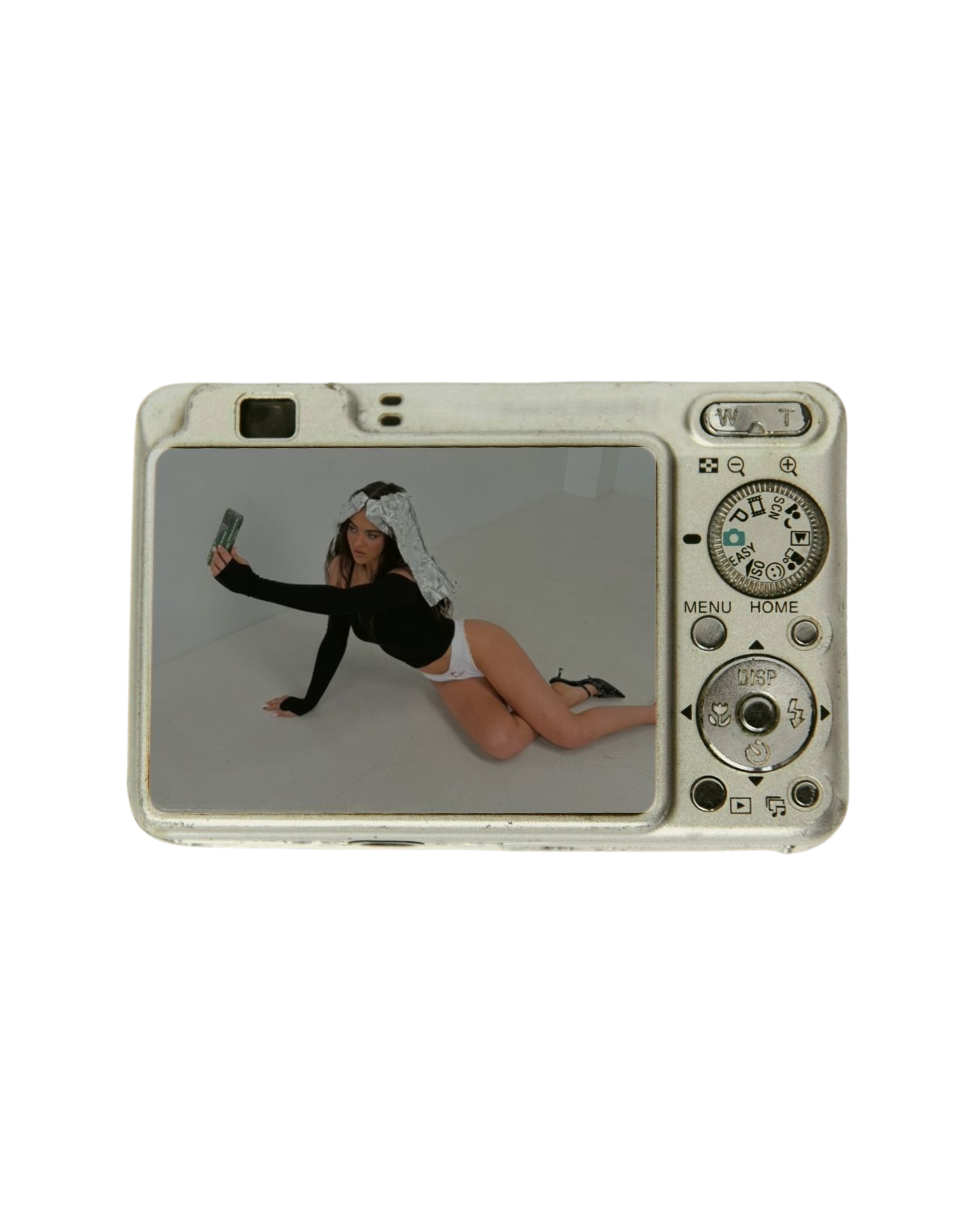 Photograph of a woman taking a selfie with a camera, kneeling on the floor, with a towel wrapped around her head, wearing a black top and white underwear.