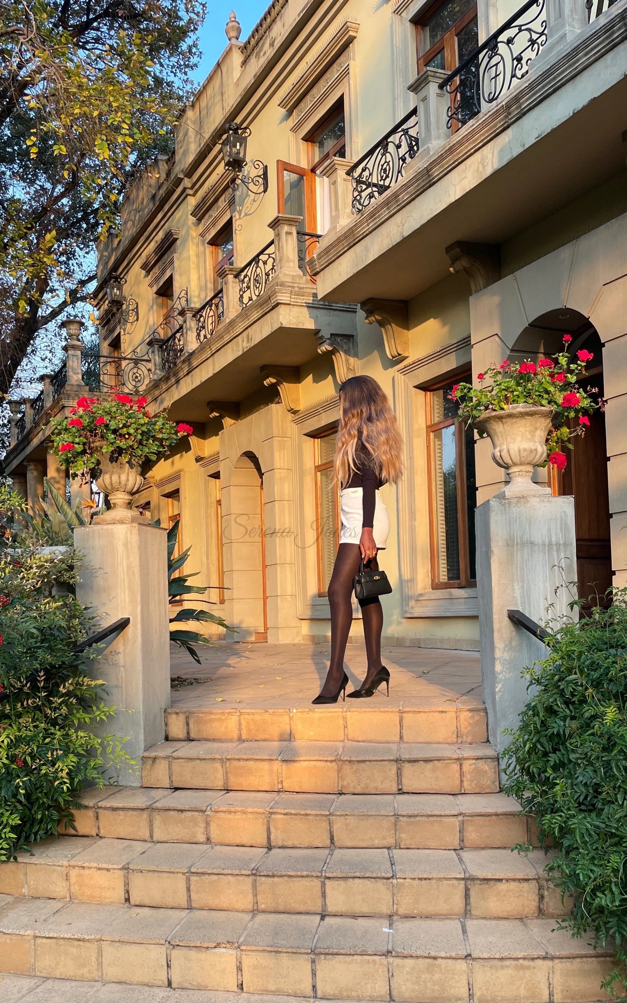 Serena Jones luxury escort Cape Town with signature blonde wavy hair standing on the stairs at beautiful luxury hotel