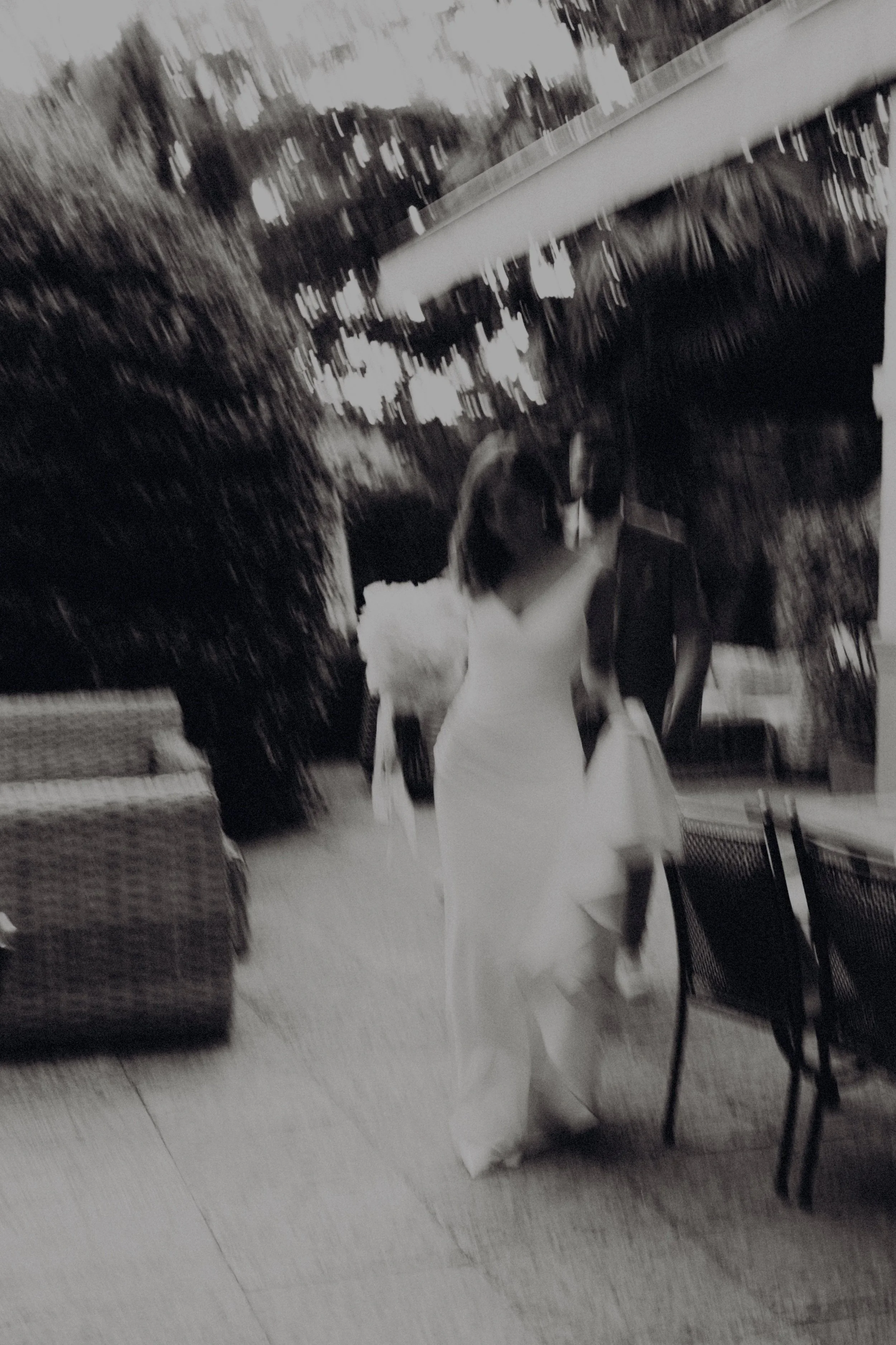 Frau in weißem Kleid und hohen Schuhen geht auf einem Gehweg, herbstliche Blätter liegen am Boden.