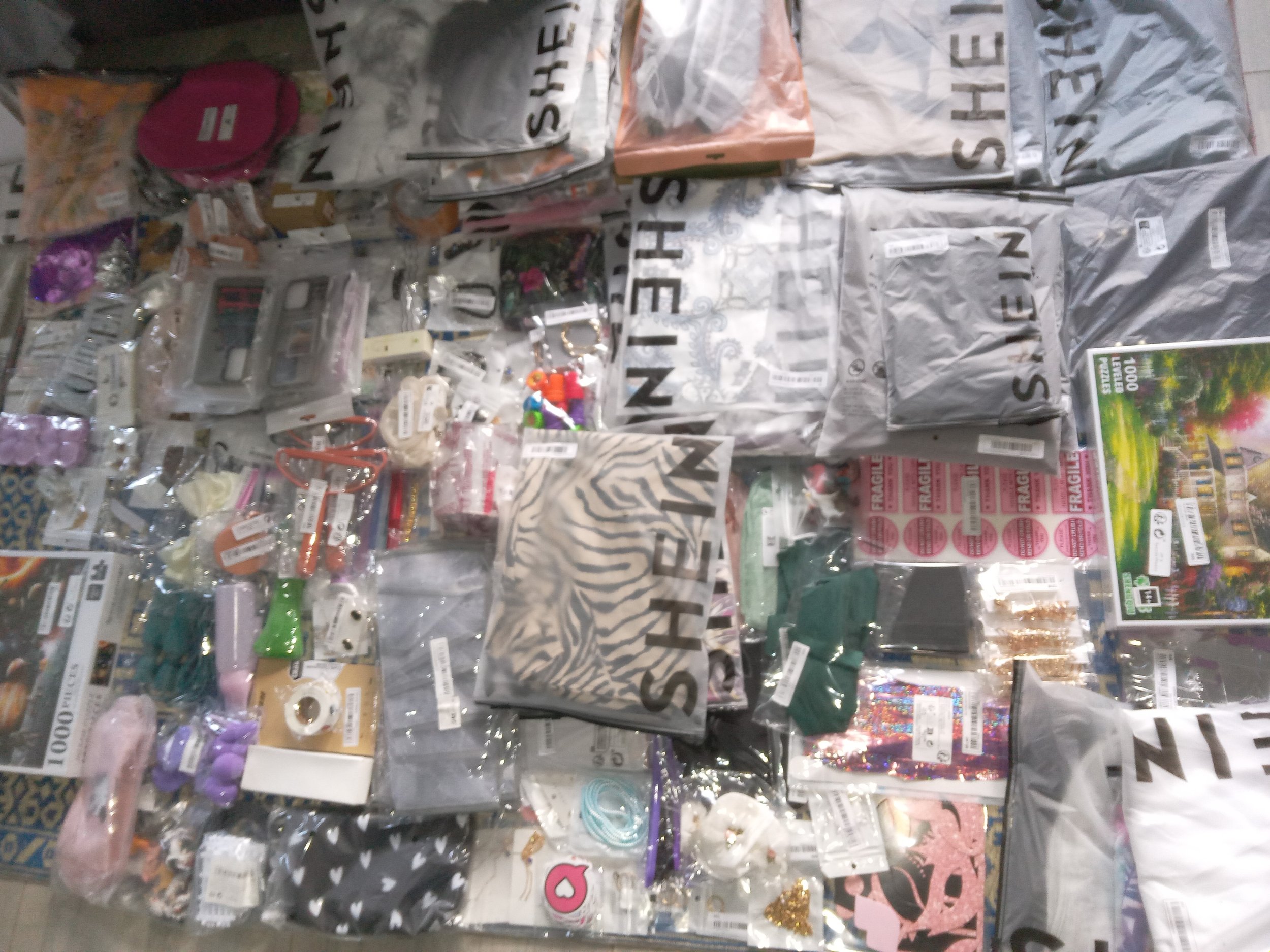 A display of various craft supplies including ribbons, stickers, decorative paper, and small craft accessories, arranged on a table in a store.