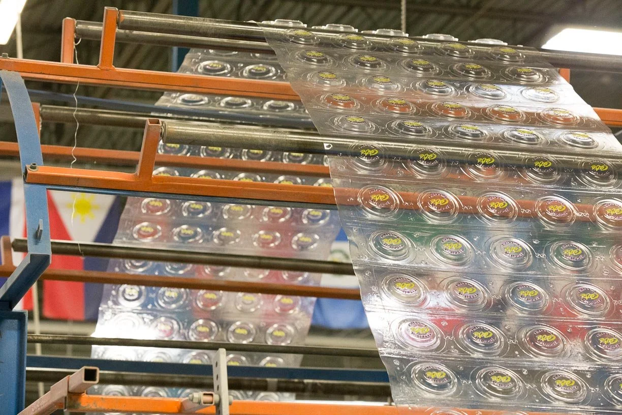 Custom branded cup lids coming off manufacturing press