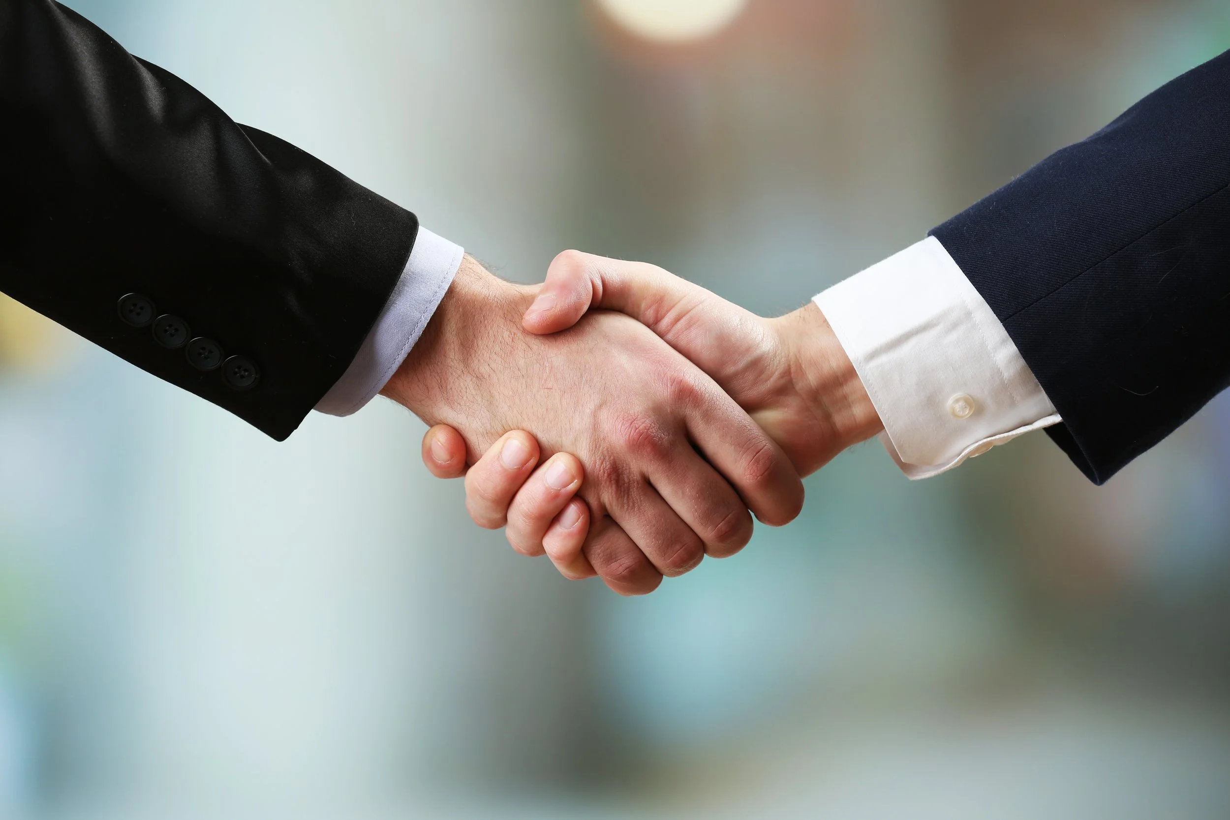 Two people in business suits shaking hands.