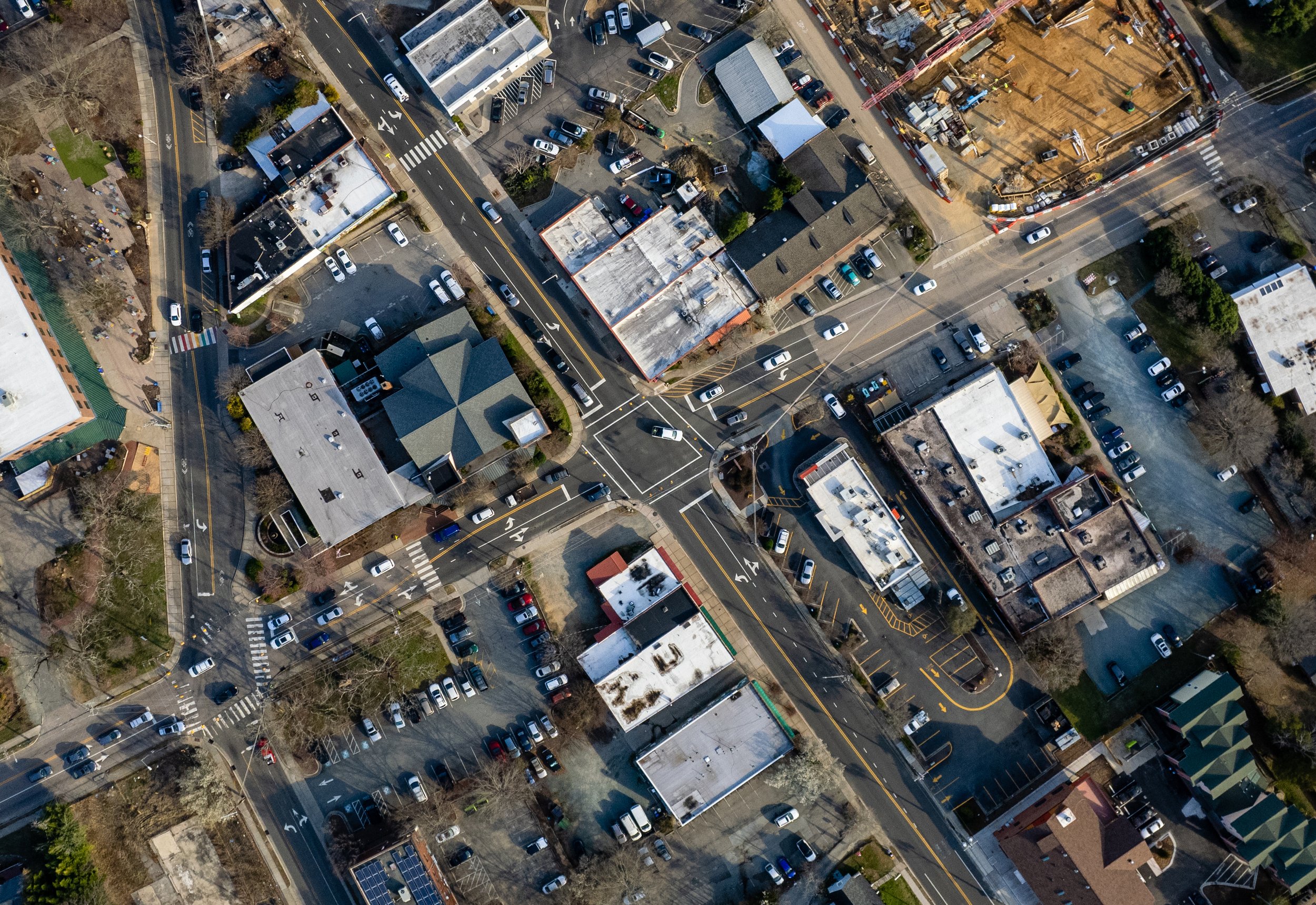 Aerial view of a small urban area with streets, parking lots, buildings, and construction site.