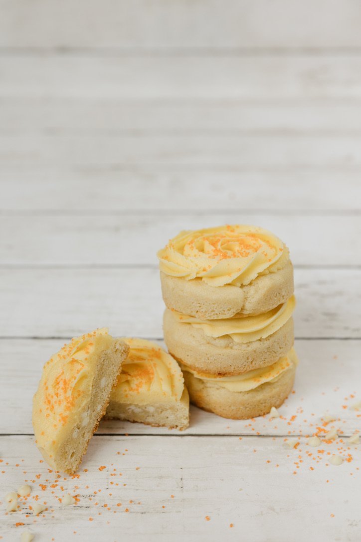 Orange Creamsicle - Soft sugar cookie loaded with orange zest & white chocolate chips, topped with a swirl of orange icing & sugar sprinkles.