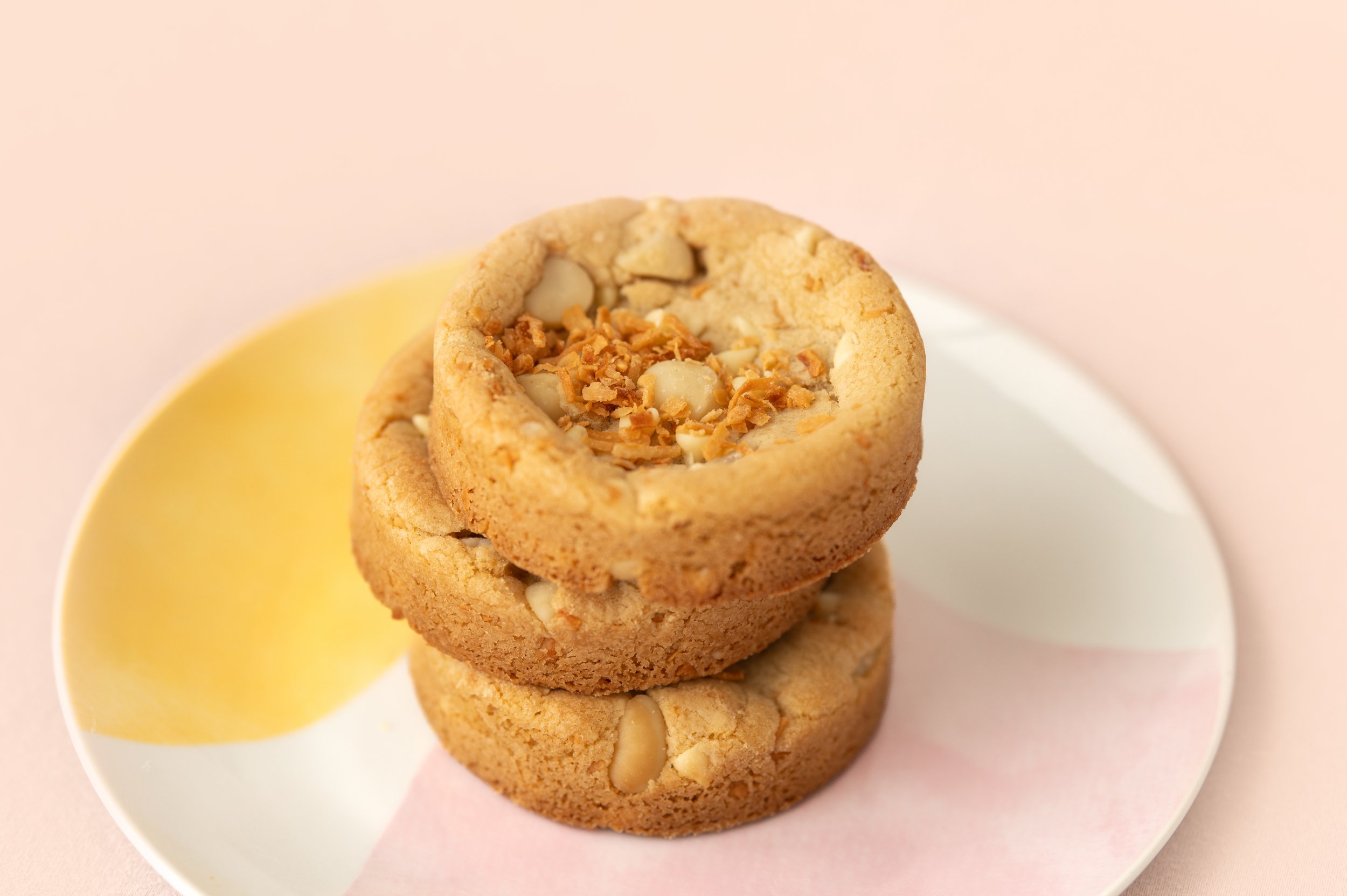 Coconut Macadamia - Buttery, brown sugar cookie dough filled with toasted coconut, white chocolate chips & macadamia nuts, topped with a sprinkle of toasted coconut.