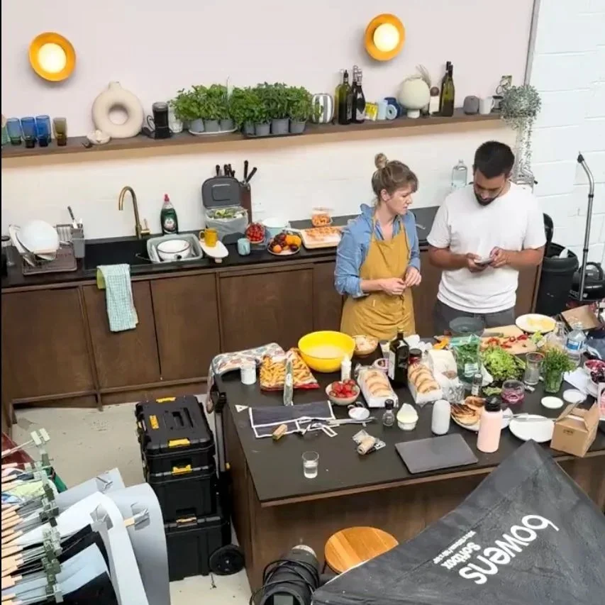 prep kitchen with food stylist and director discussing food for photoshoot. Fresh food laid on kitchen island with seafood, herbs, bowls, oils