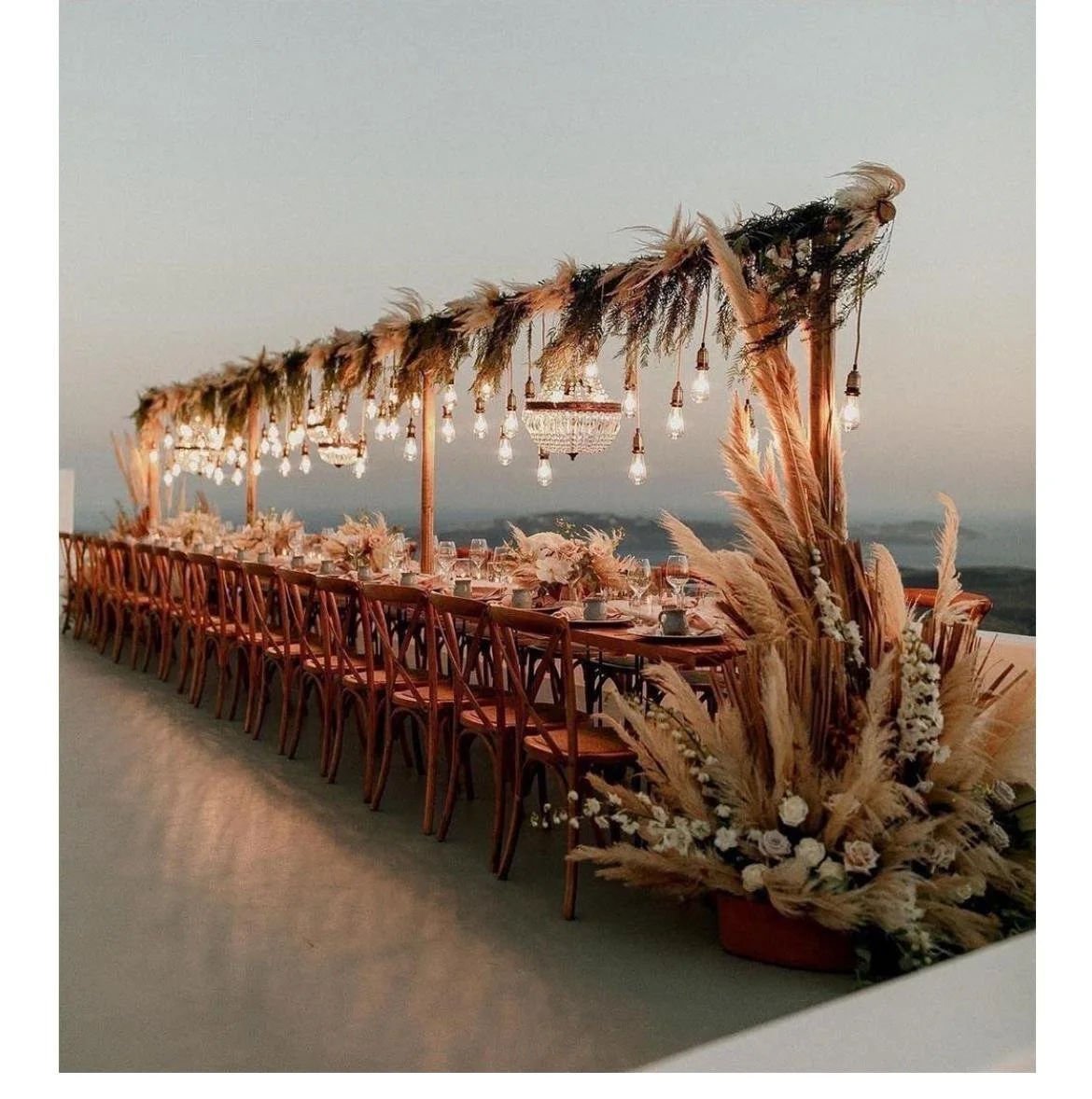 A luxury outdoor wedding reception in Greece with pampas grass and hanging lights planned by Lalla Crippa destination wedding planner
