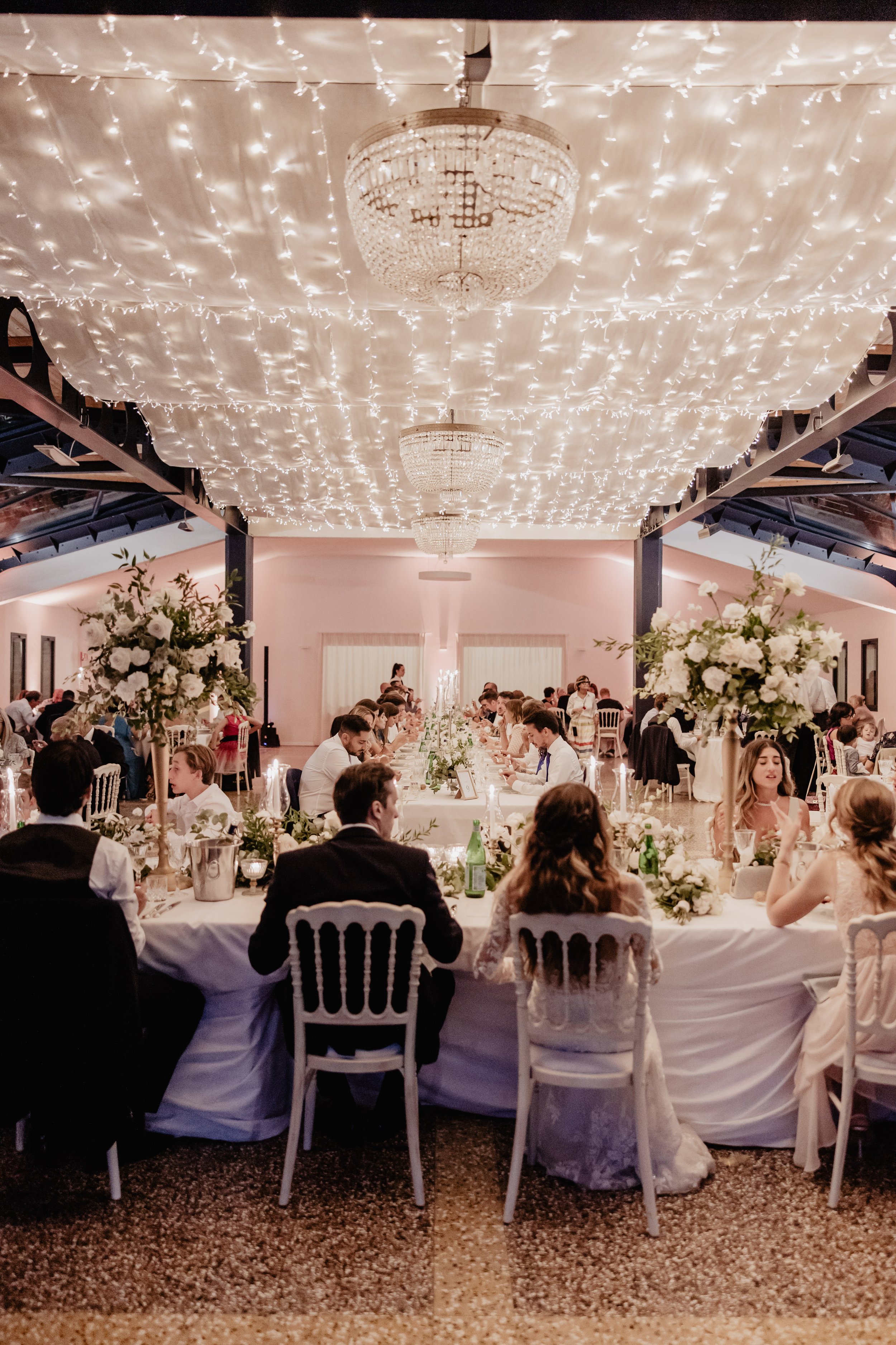 A luxury indoor wedding reception on Lake Como with fairy lights and chandeliers planned by Lalla Crippa