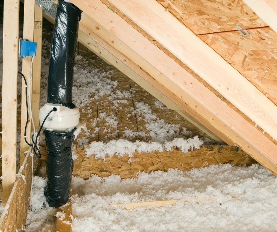 Attic insulation installation with blown-in white insulation material, wooden framing, and electrical wiring.