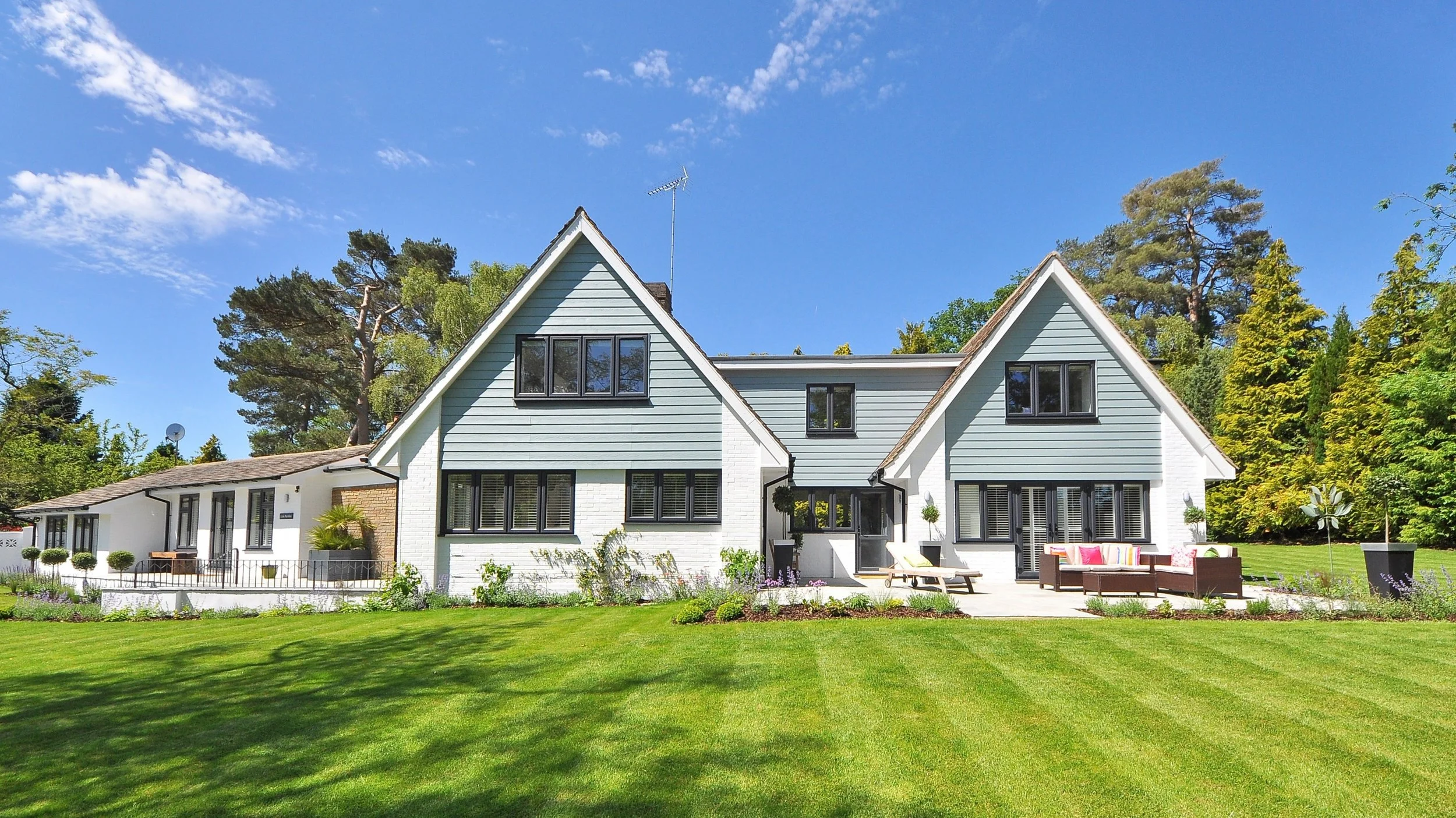 Modern house with green lawn and outdoor seating on a sunny day
