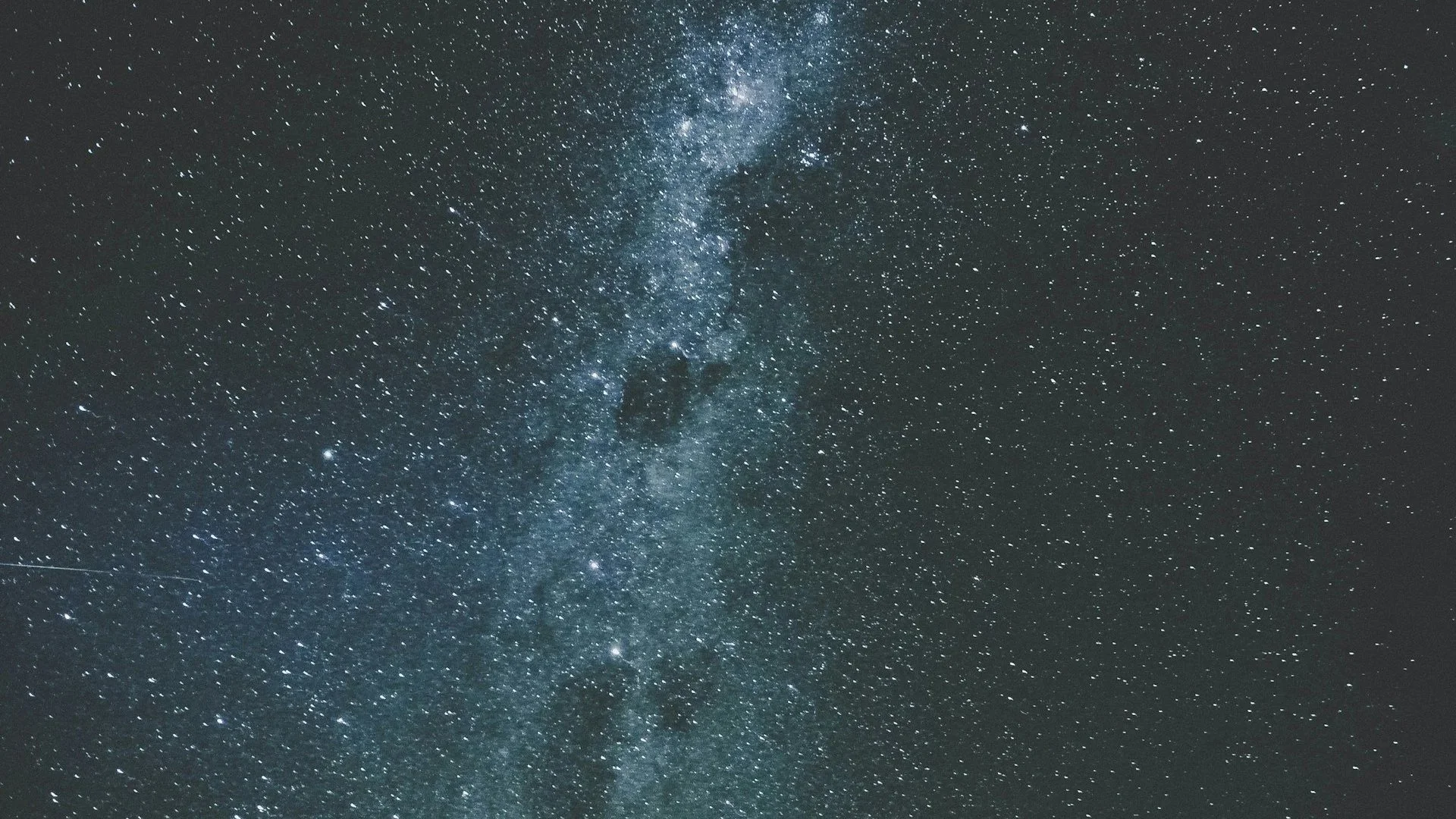 A clear, starry night sky over New Zealand featuring a vibrant view of the Milky Way galaxy stretching across the frame.