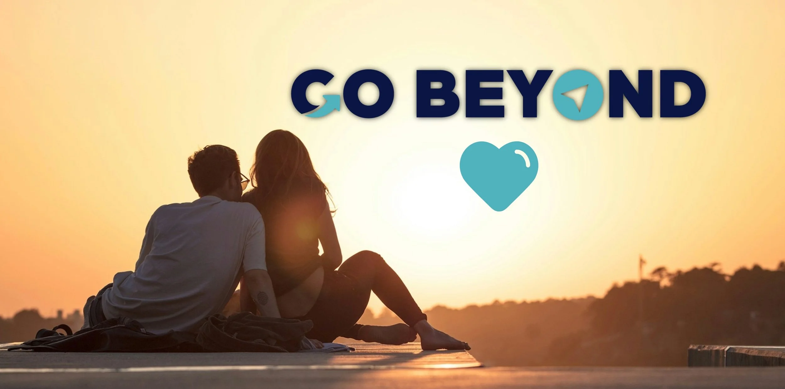 A couple sits together on a pier at sunset, looking out at the horizon. Overlaid is a logo that reads "GO BEYOND" with a teal heart icon.