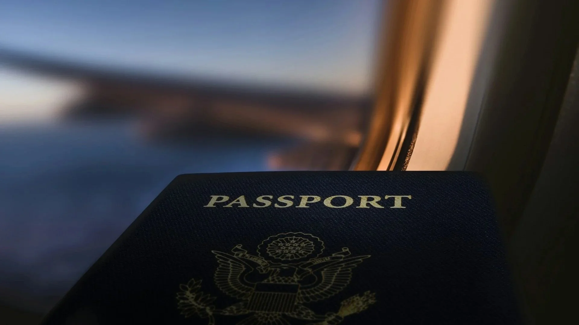 United States passport resting by an airplane window during a flight.