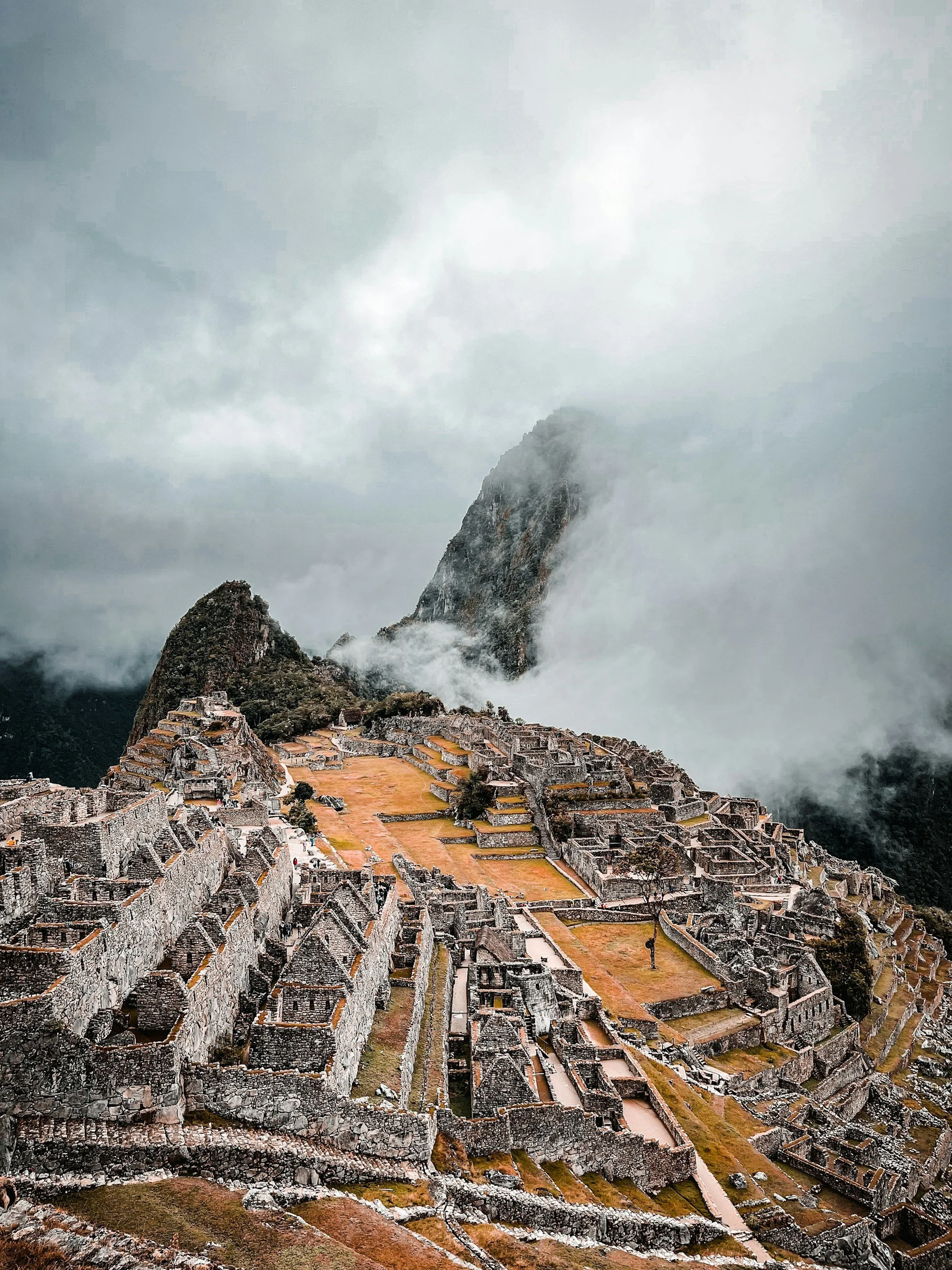 A dramatic, high-angle view of the Machu Picchu stone citadel partially shrouded in morning mist.