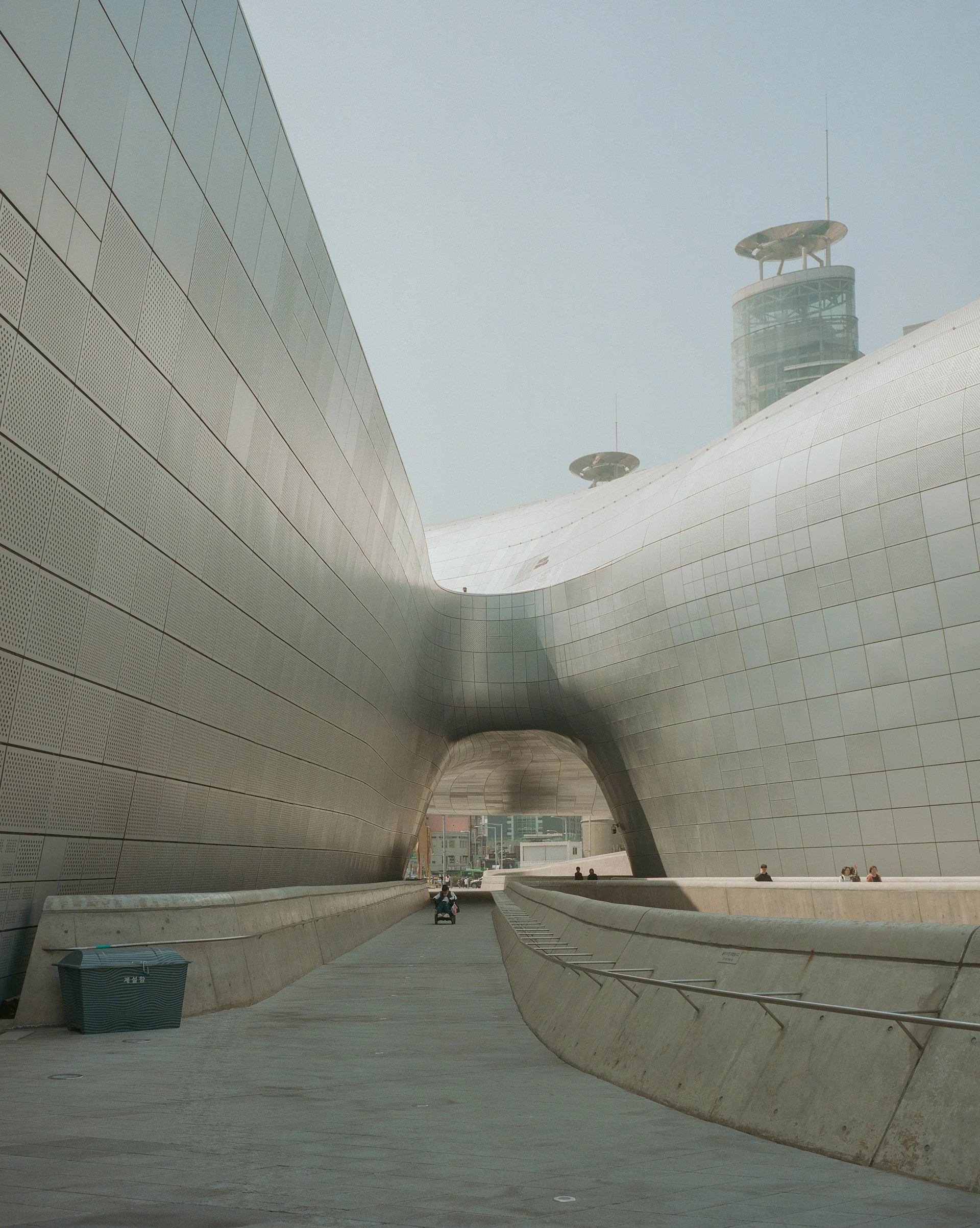 A view of the sleek, curved metallic exterior of the Dongdaemun Design Plaza in Seoul.
