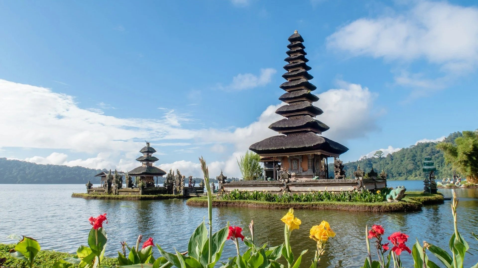 The Pura Ulun Danu Bratan water temple with its multi-tiered thatched roofs on the edge of a calm lake.