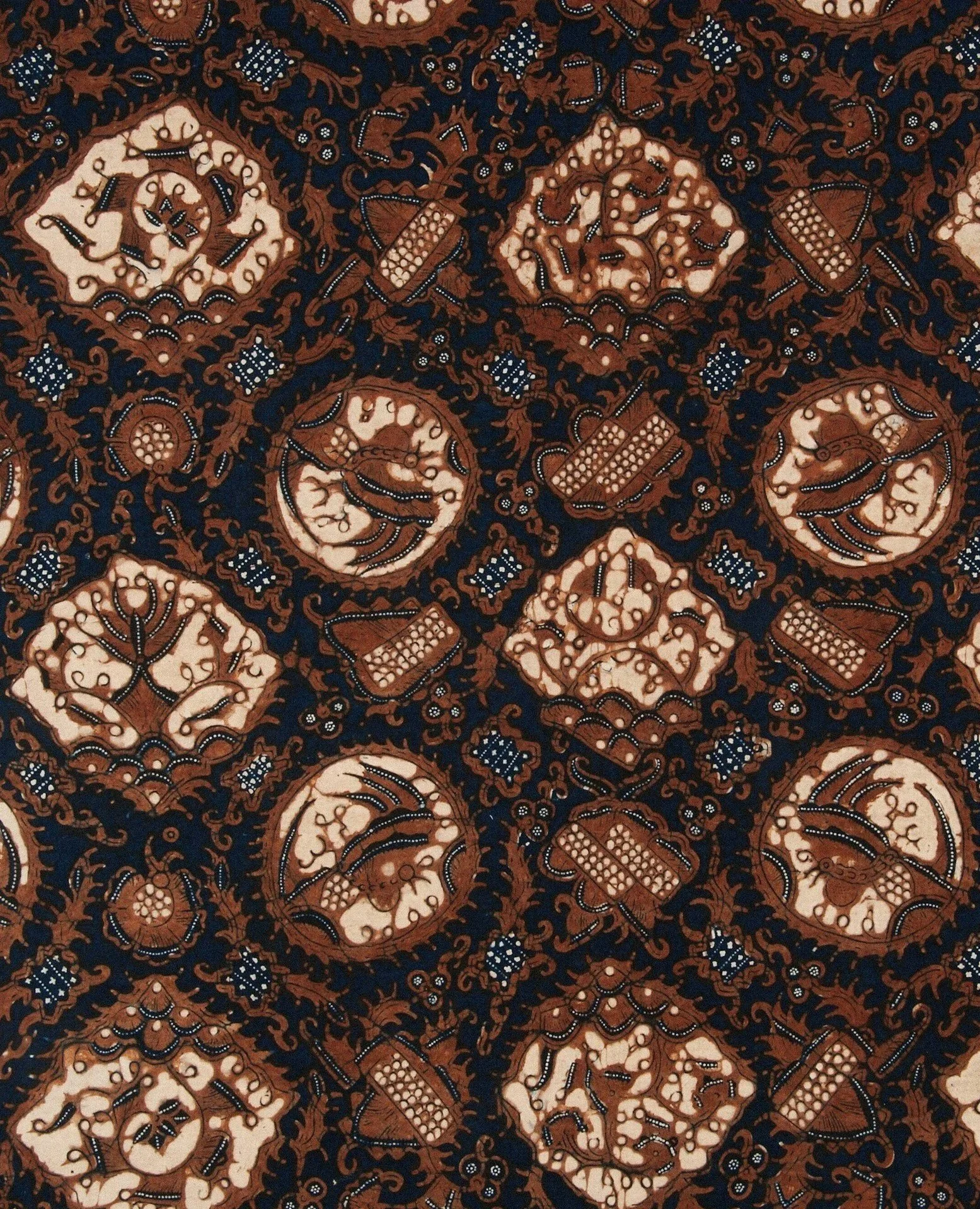 A detailed traditional Indonesian batik pattern featuring intricate floral and geometric motifs in shades of brown, indigo, and cream.