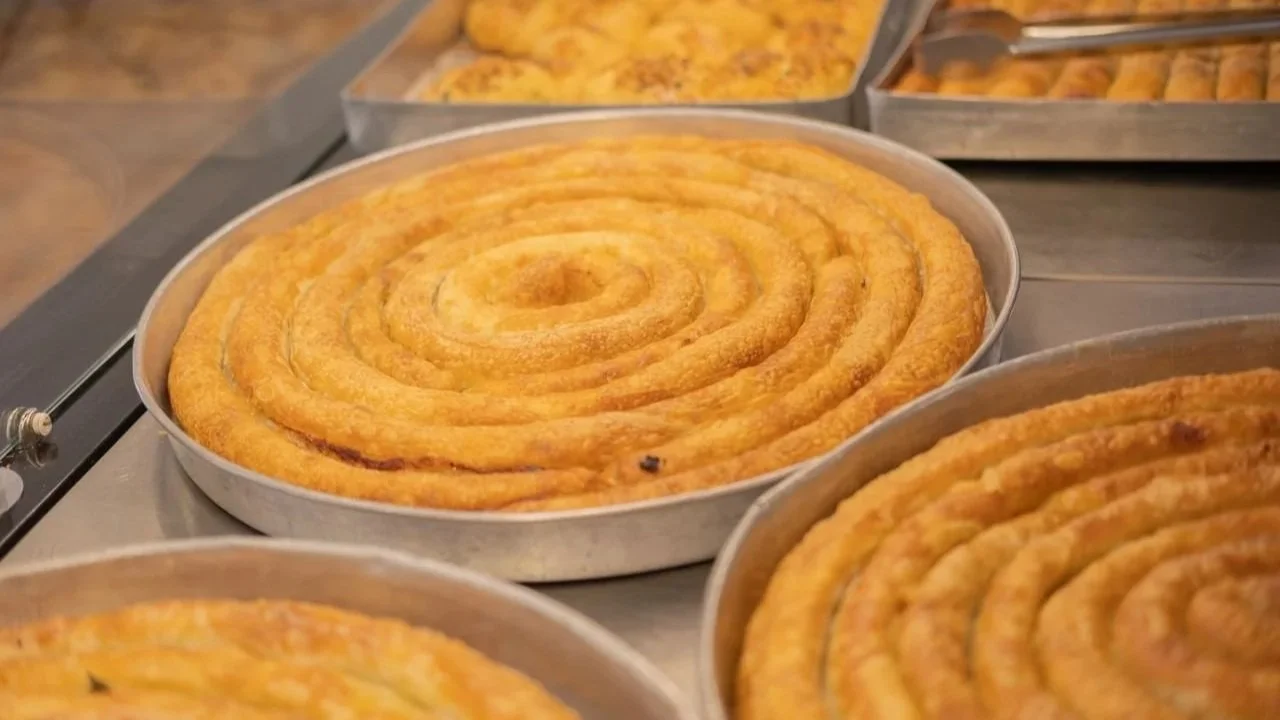 Golden, spiral-baked pastry pies sitting in round metal trays in a display case.