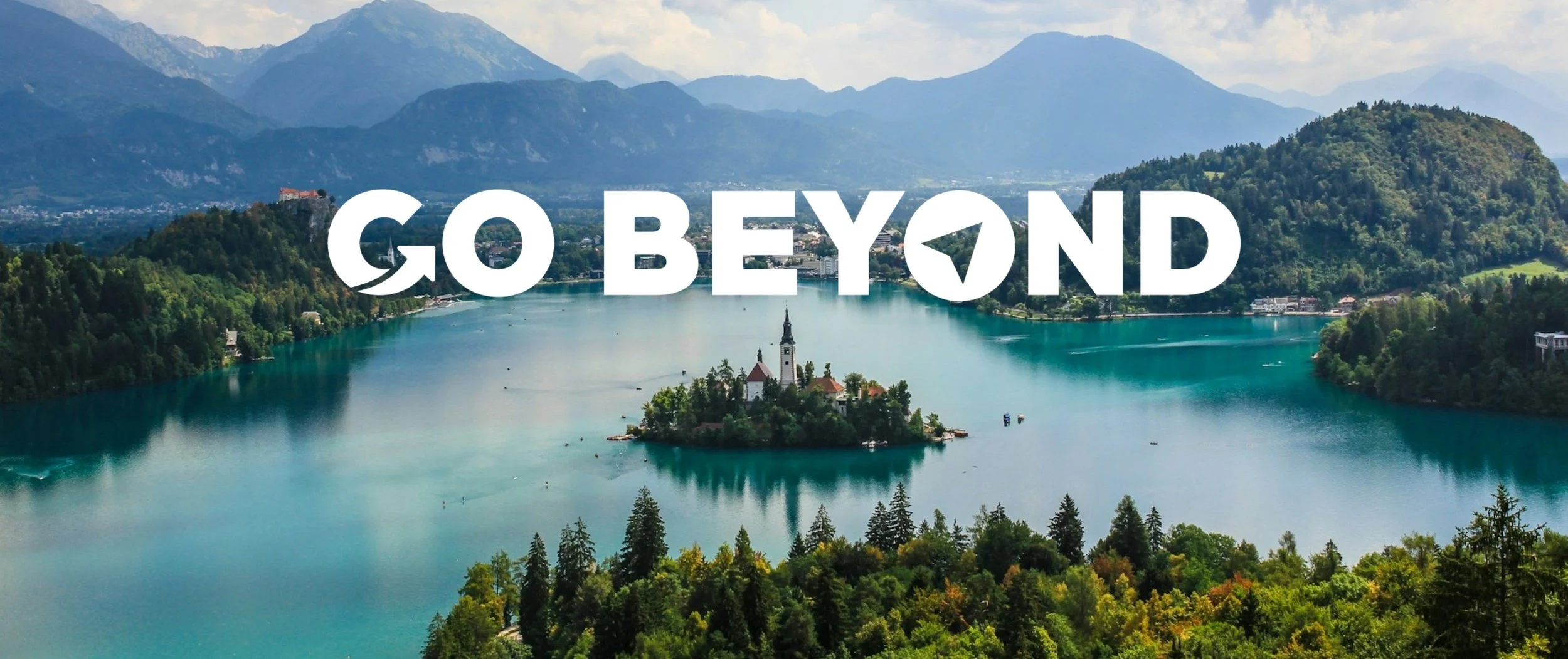 A scenic view of Slovenia's green landscape, featuring rolling hills, dense forests, and a clear blue sky.