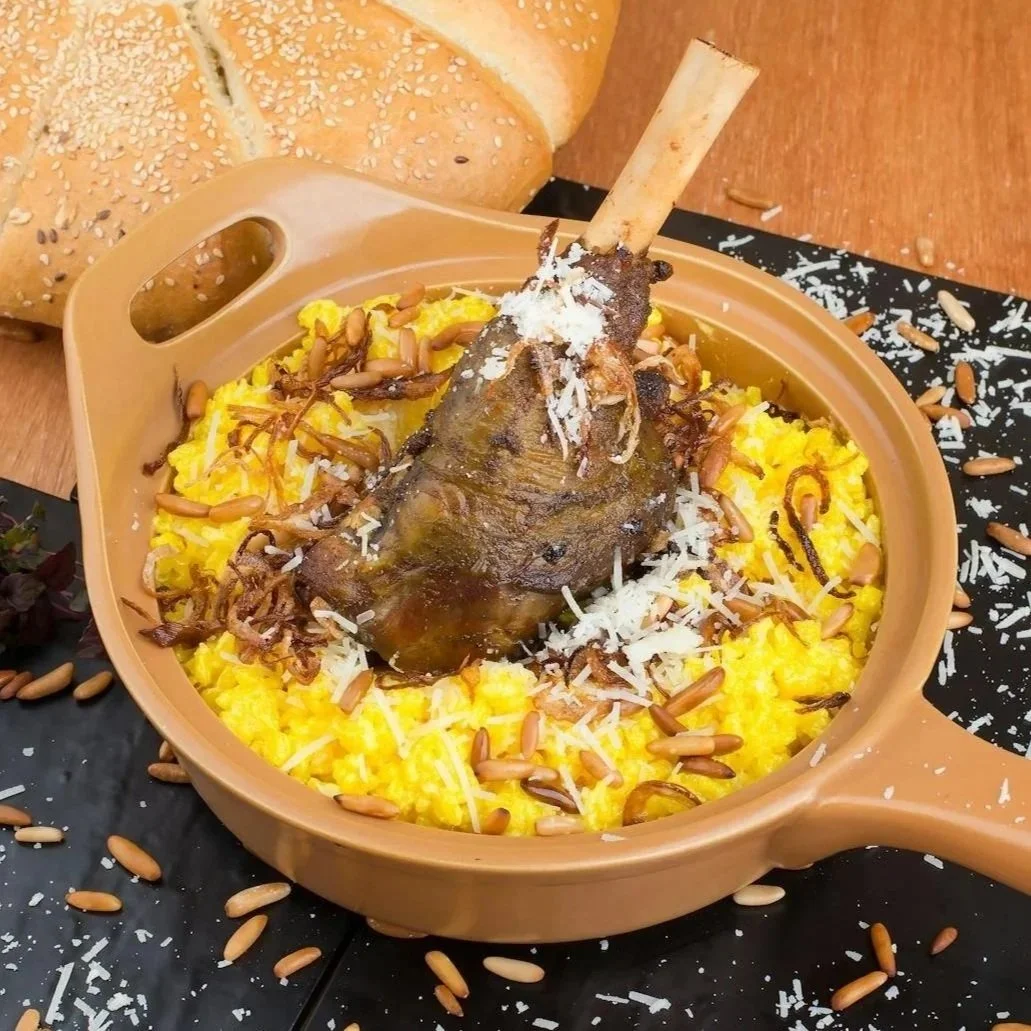 Deliciously plated lamb shank atop saffron risotto garnished with herbs and pine nuts