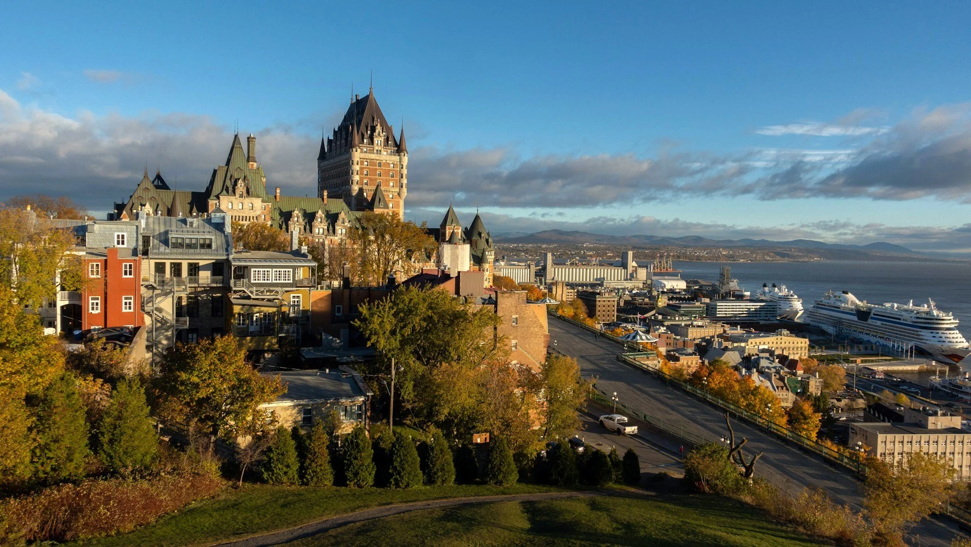 An elevated view of Old Quebec City featuring the historic Fairmont Le Château Frontenac and a cruise ship in the harbor.