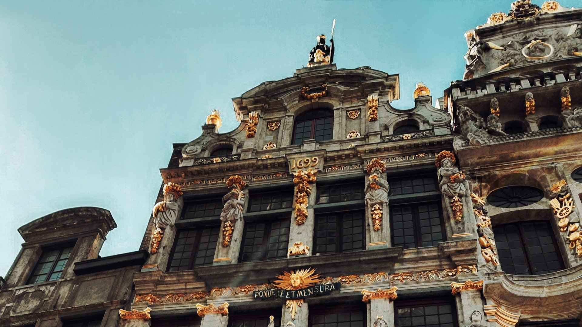 Ornate historic guildhouse facade with intricate gold detailing at the Grand-Place in Brussels against a clear sky.