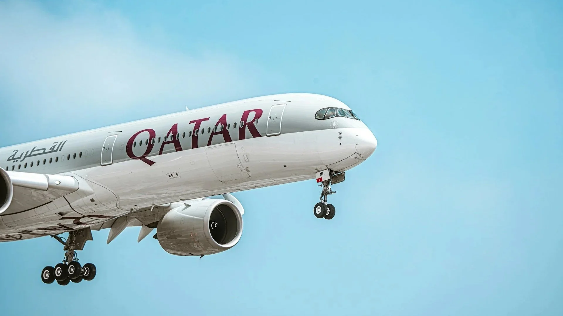 A Qatar Airways passenger airplane descending for arrival at Hamad International Airport in Doha.