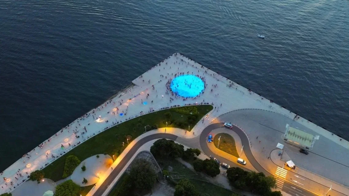 Aerial view of "The Greeting to the Sun" light installation on the Zadar waterfront at dusk.