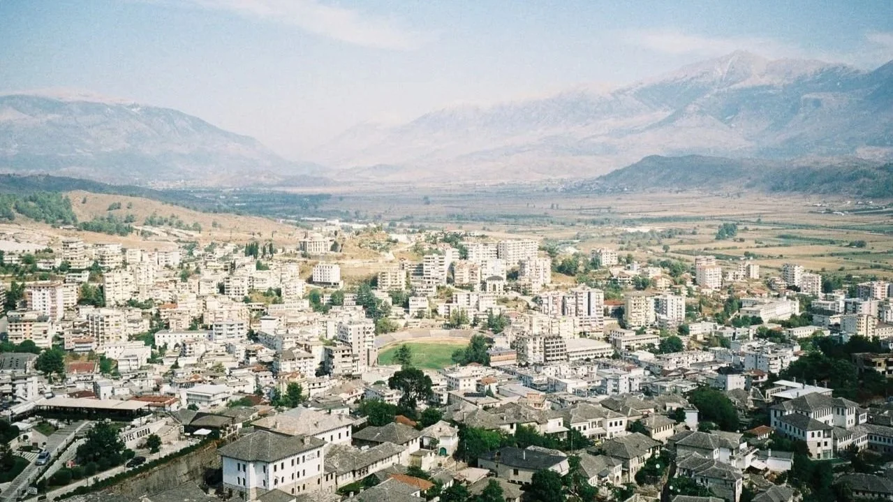 Aerial panoramic view of a densely populated valley town backed by hazy mountains.