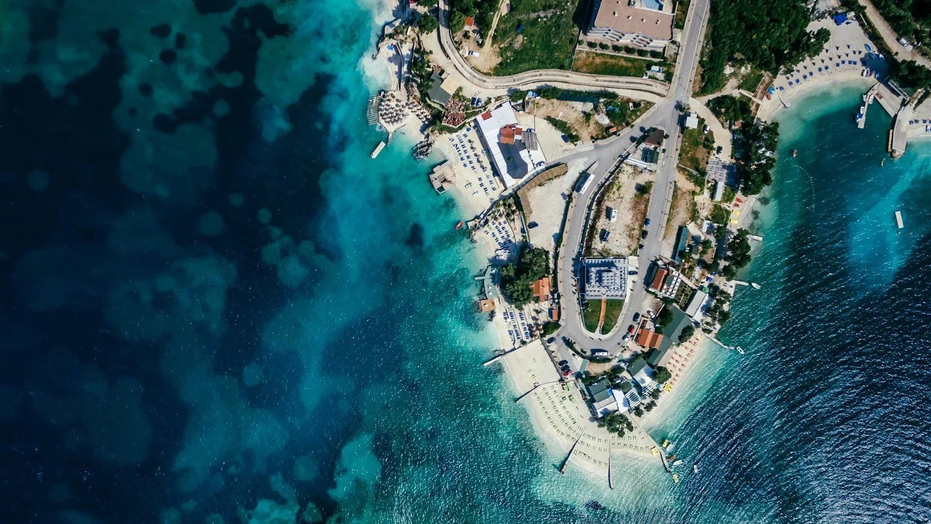 Aerial view of a tropical coastal peninsula surrounded by vibrant, clear blue waters.