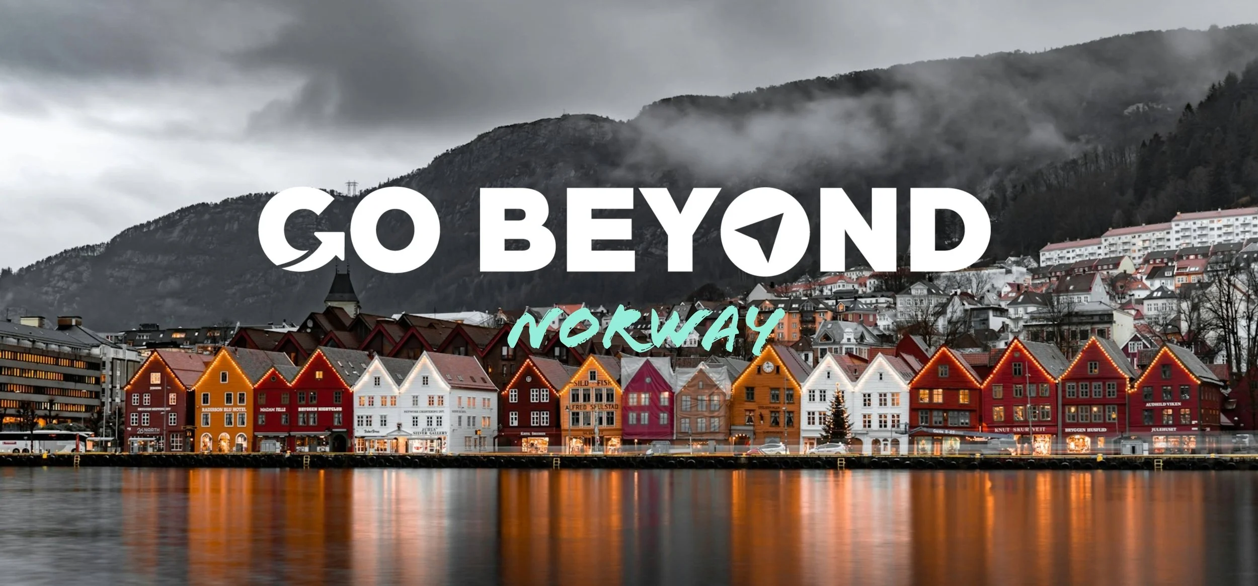 A row of colorful historic wooden buildings along a waterfront at dusk with "GO BEYOND NORWAY" text overlaid.