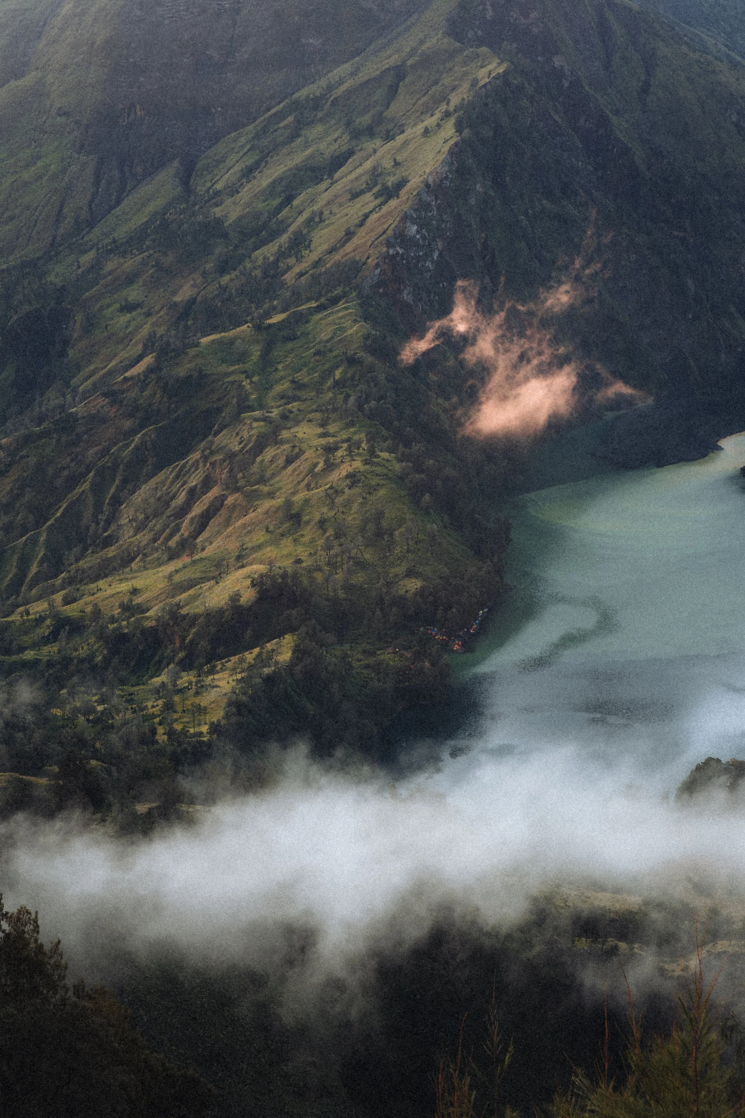 Paysage montagneux avec un lac, nuages et végétation verte.Mont Rinjani