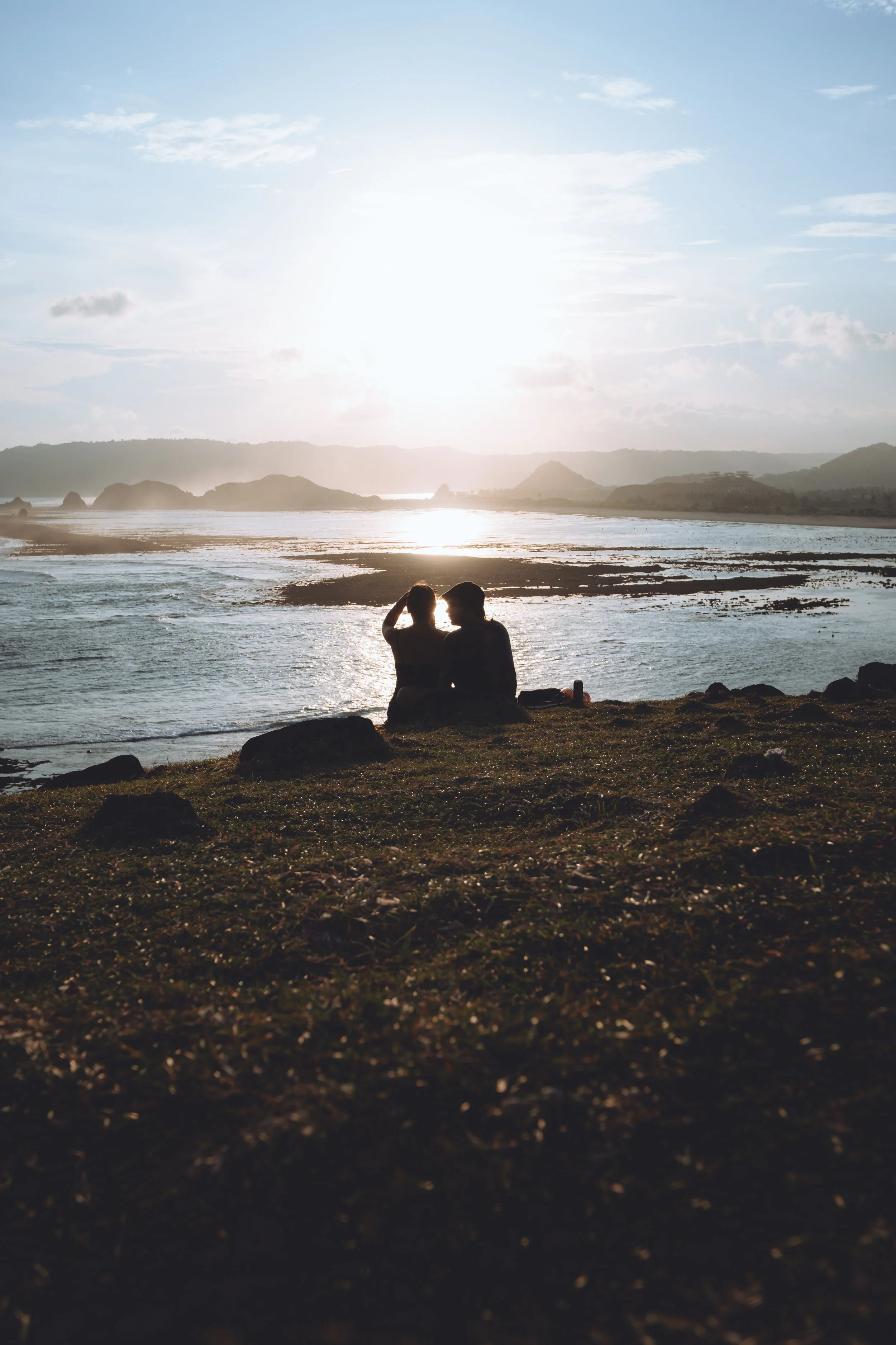 Deux personnes assises sur la plage regardant le coucher de soleil sur l'océan