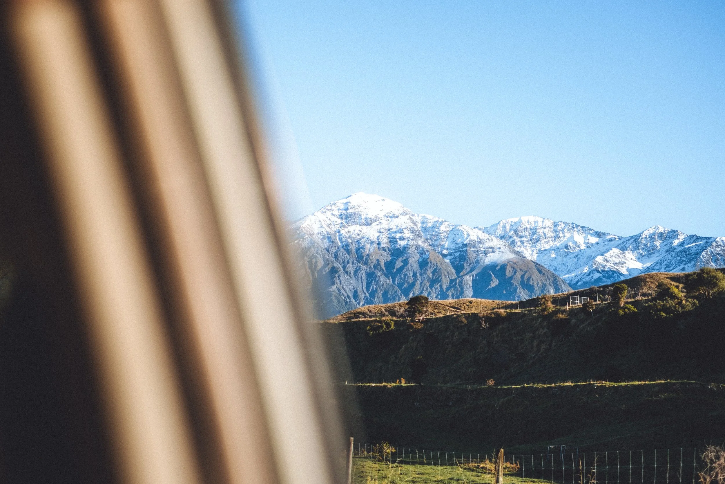 Vue d'une montagne enneigée vue depuis une fenêtre d'avion ou de train, avec un ciel clair.