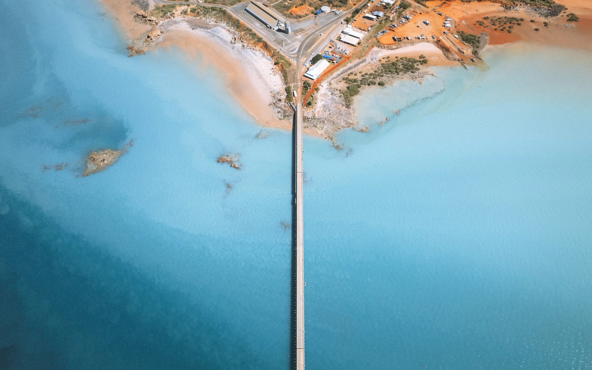 Photo aérienne montrant un pont traversant un lac, avec des zones sèches et quelques bâtiments en arrière-plan. Darwin, Australia