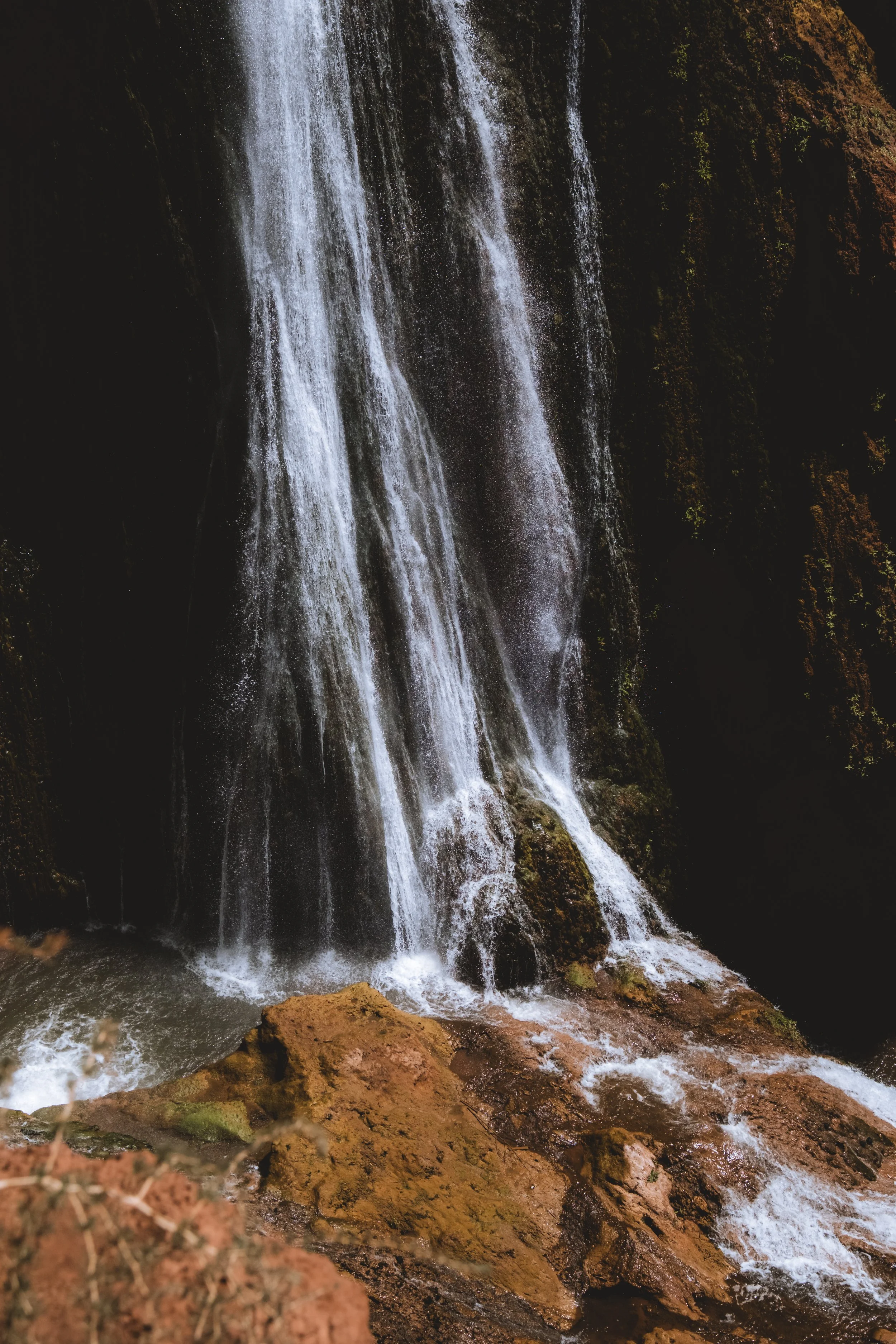 Chute d'eau dans un environnement naturel rocheux et boisé.